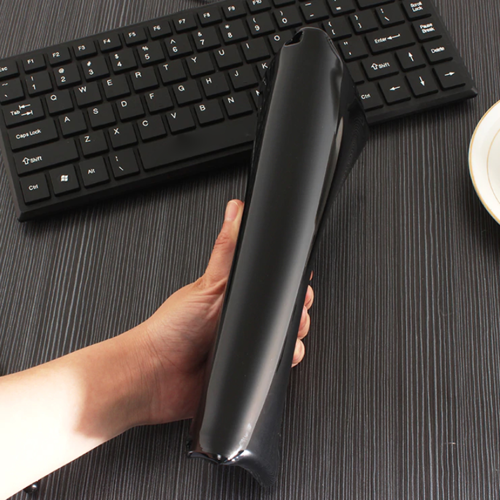 Eine schwarze Tablethülle, die von einer Hand gehalten wird, mit einer Tastatur im Hintergrund.