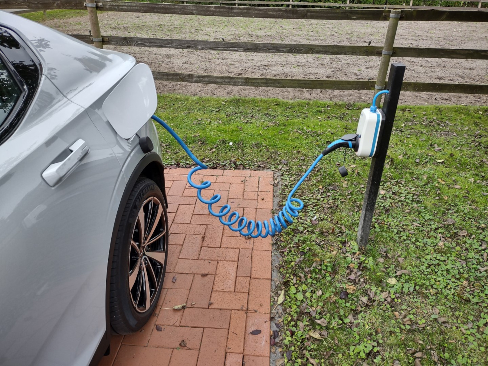 Ein Elektroauto wird geladen. Es hat ein blaues Kabel und eine Ladestation.