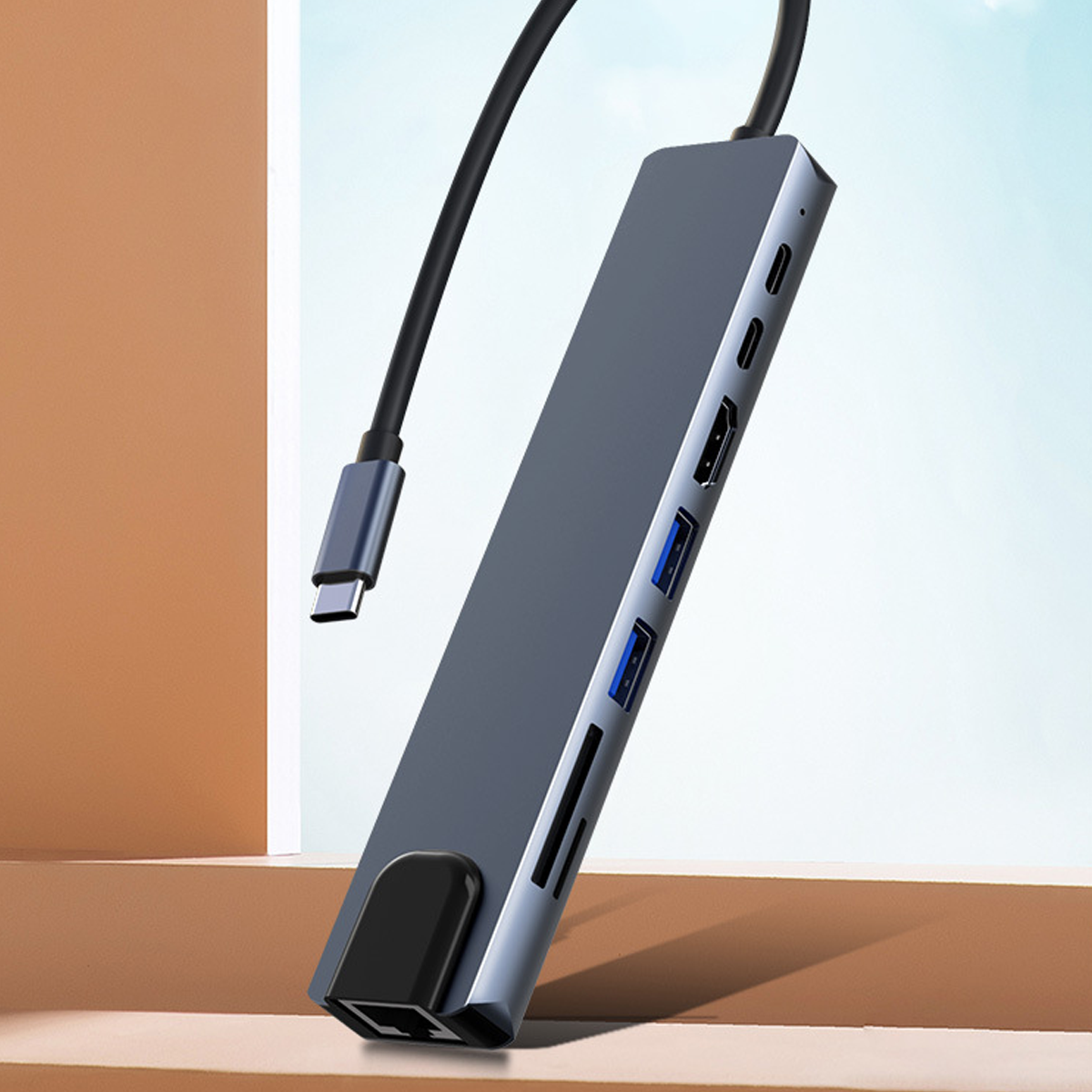 Grauer und silberner Hub mit mehreren Anschlüssen, USB-C-Kabel. Blauer Hintergrund.