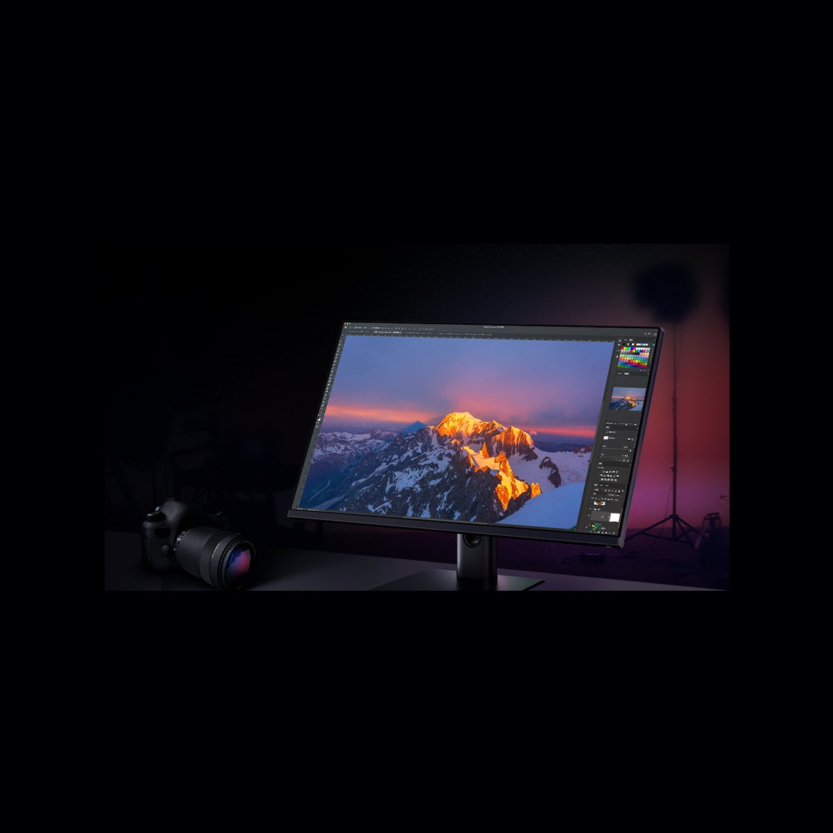 Monitor komputera wyświetlający górski krajobraz z widocznym oprogramowaniem do edycji. Aparat po lewej.