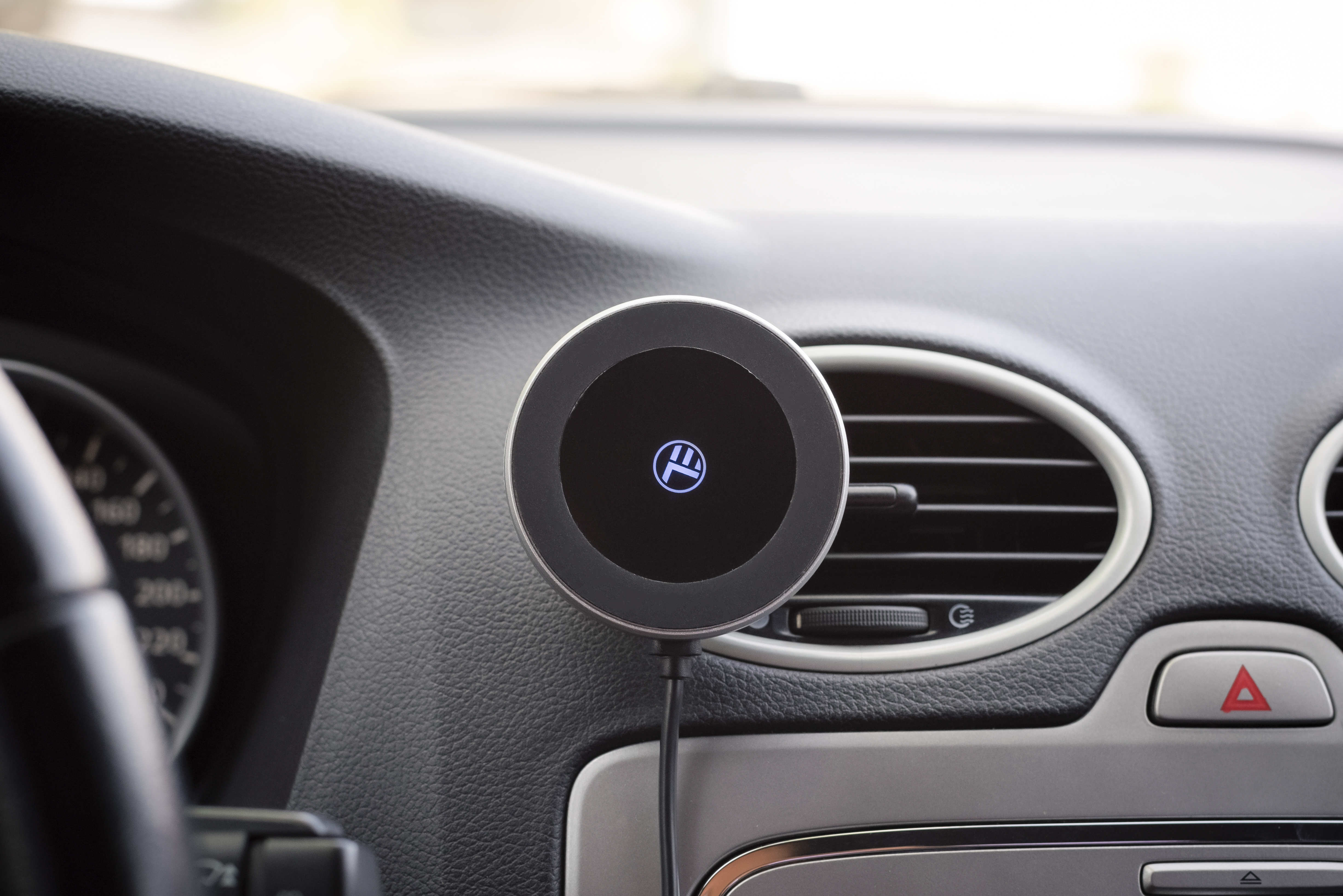 Czarna deska rozdzielcza z okrągłą ładowarką bezprzewodową. Wyświetlacz pokazuje logo.