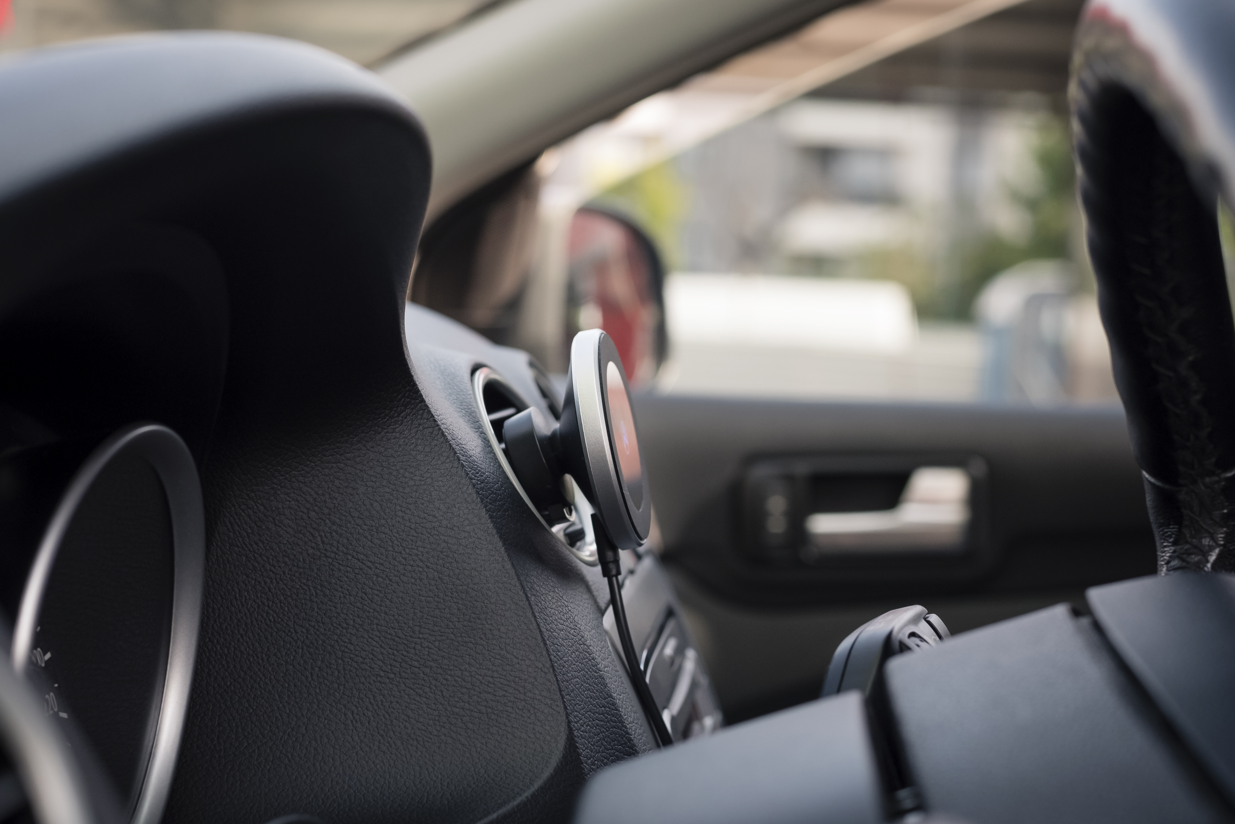 Widok wnętrza samochodu, pokazujący uchwyt na telefon na desce rozdzielczej i część kierownicy.