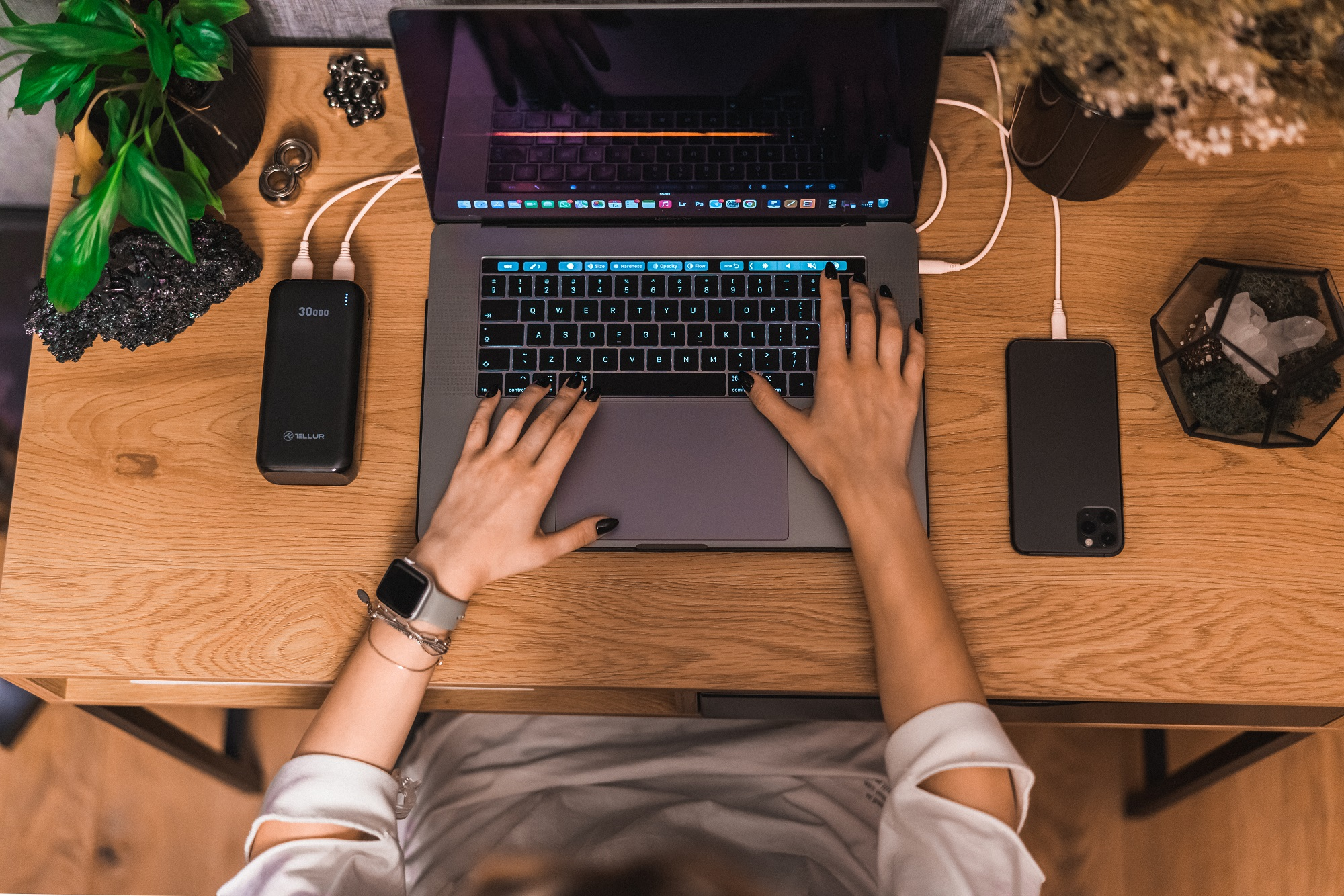 Widok z góry na osobę korzystającą z laptopa z power bankiem i telefonem.
