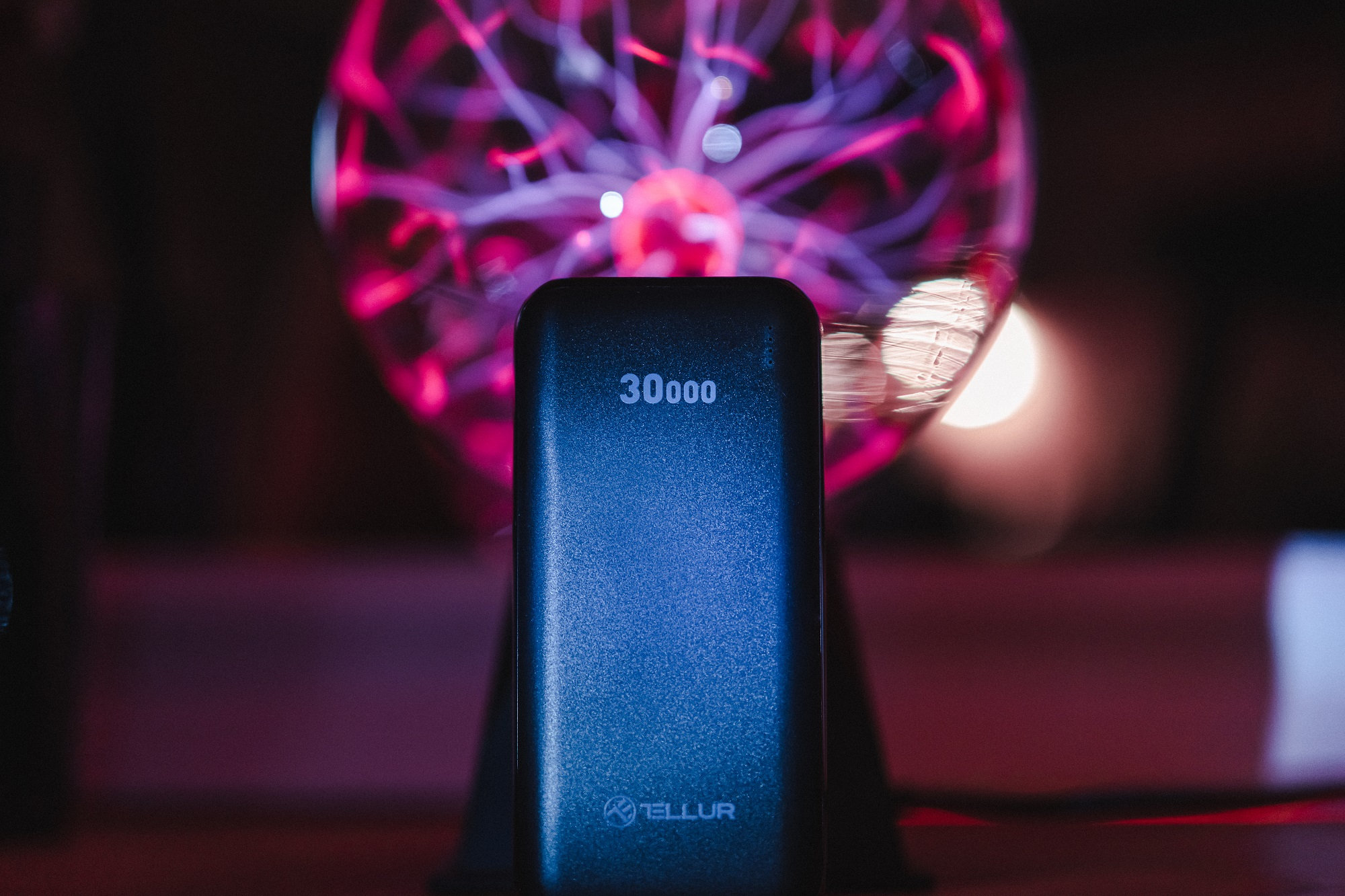 Czarny power bank z napisem 30000, z kulą plazmową w tle.