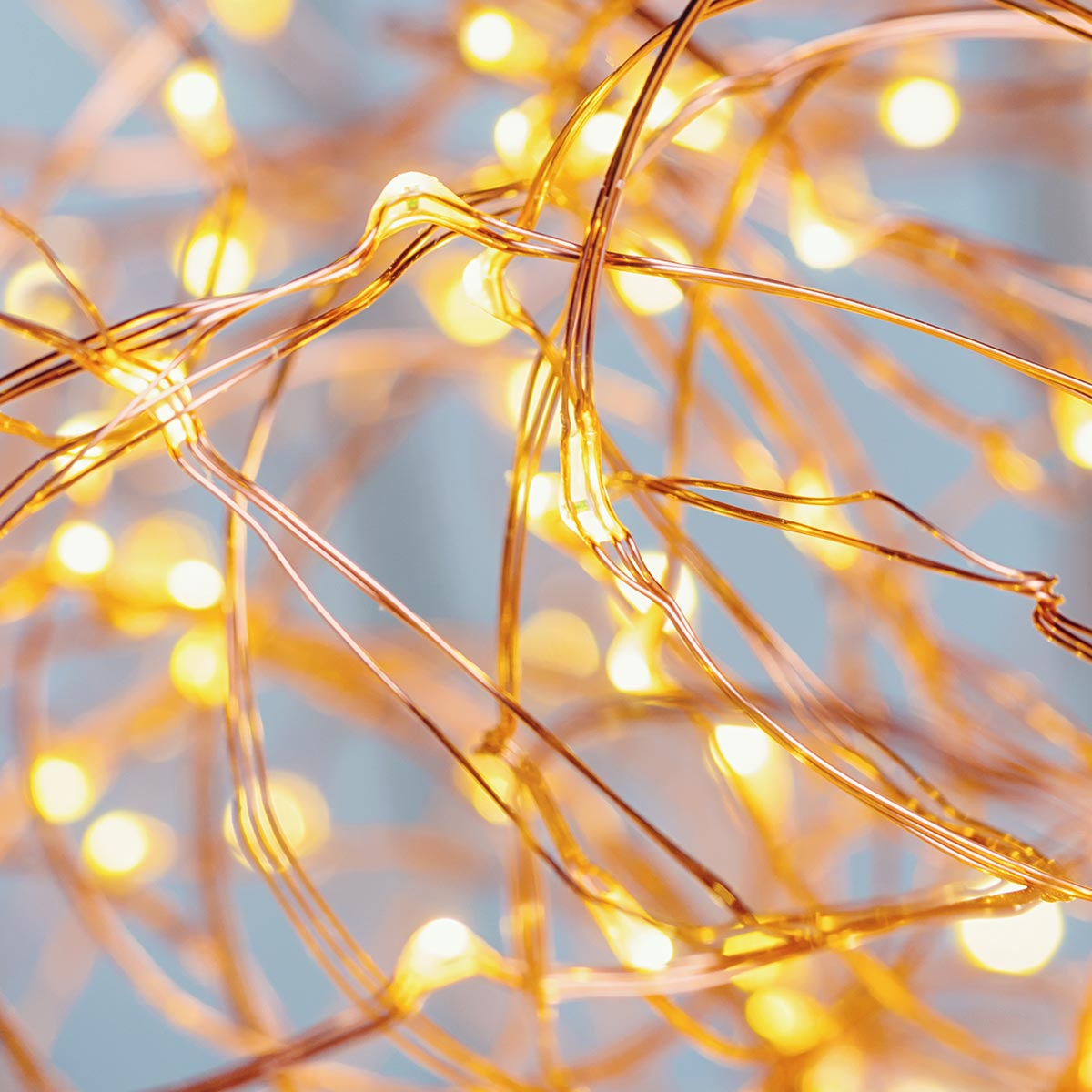 Kupferdrahtlichter mit gelben Glühbirnen. Der Hintergrund ist blau.
