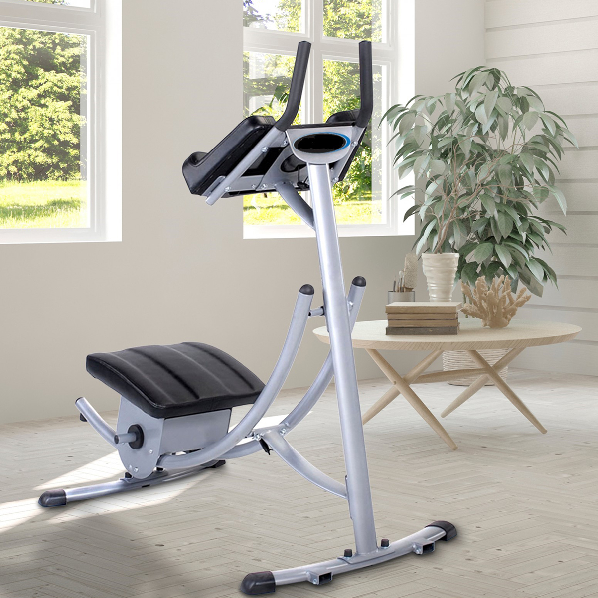 Appareil d'exercice de gym dans une pièce avec lumière naturelle. L'appareil est argenté et noir, avec un siège et des poignées. Table et plante à proximité.