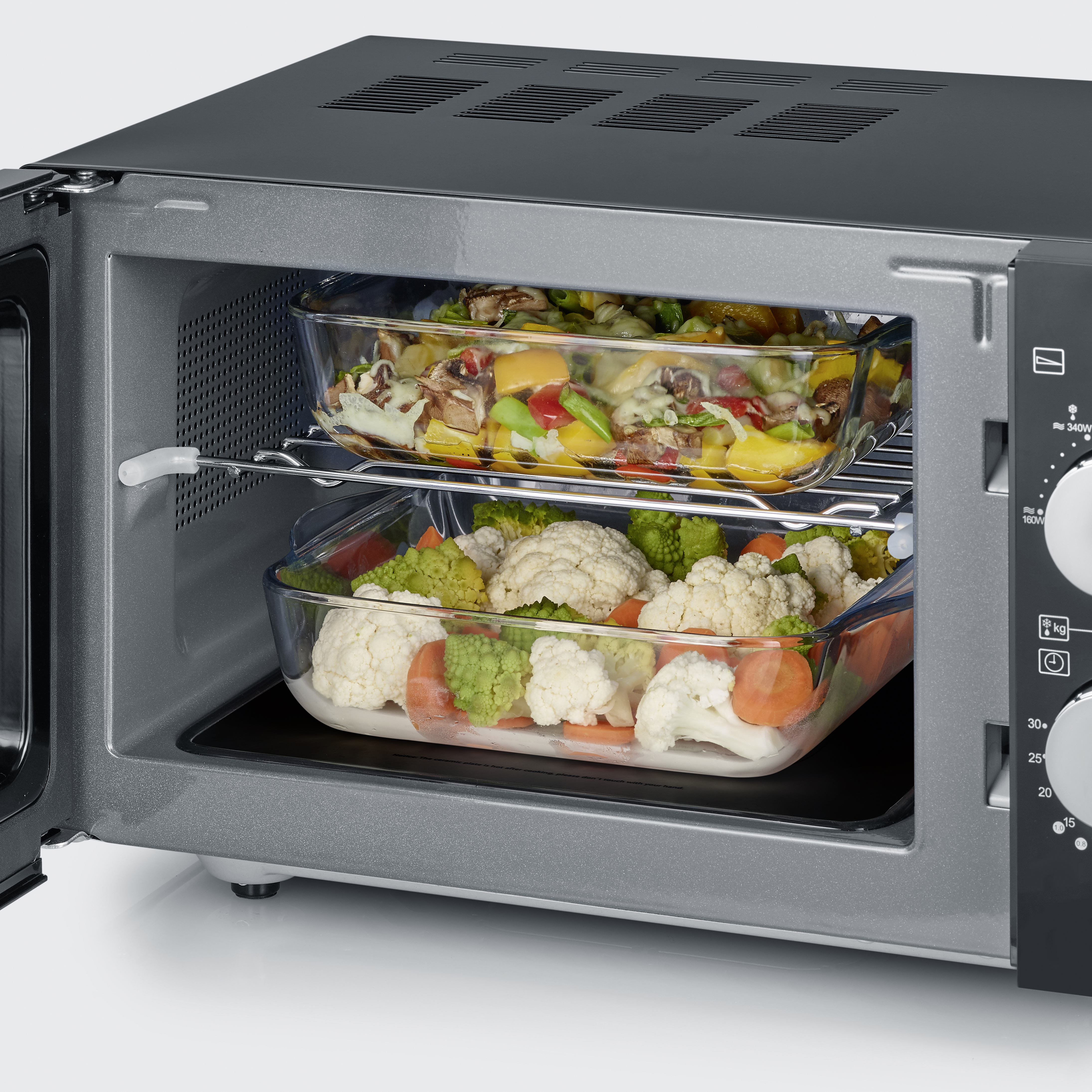 Kuchenka mikrofalowa z dwoma szklanymi naczyniami w środku, wypełnionymi jedzeniem.