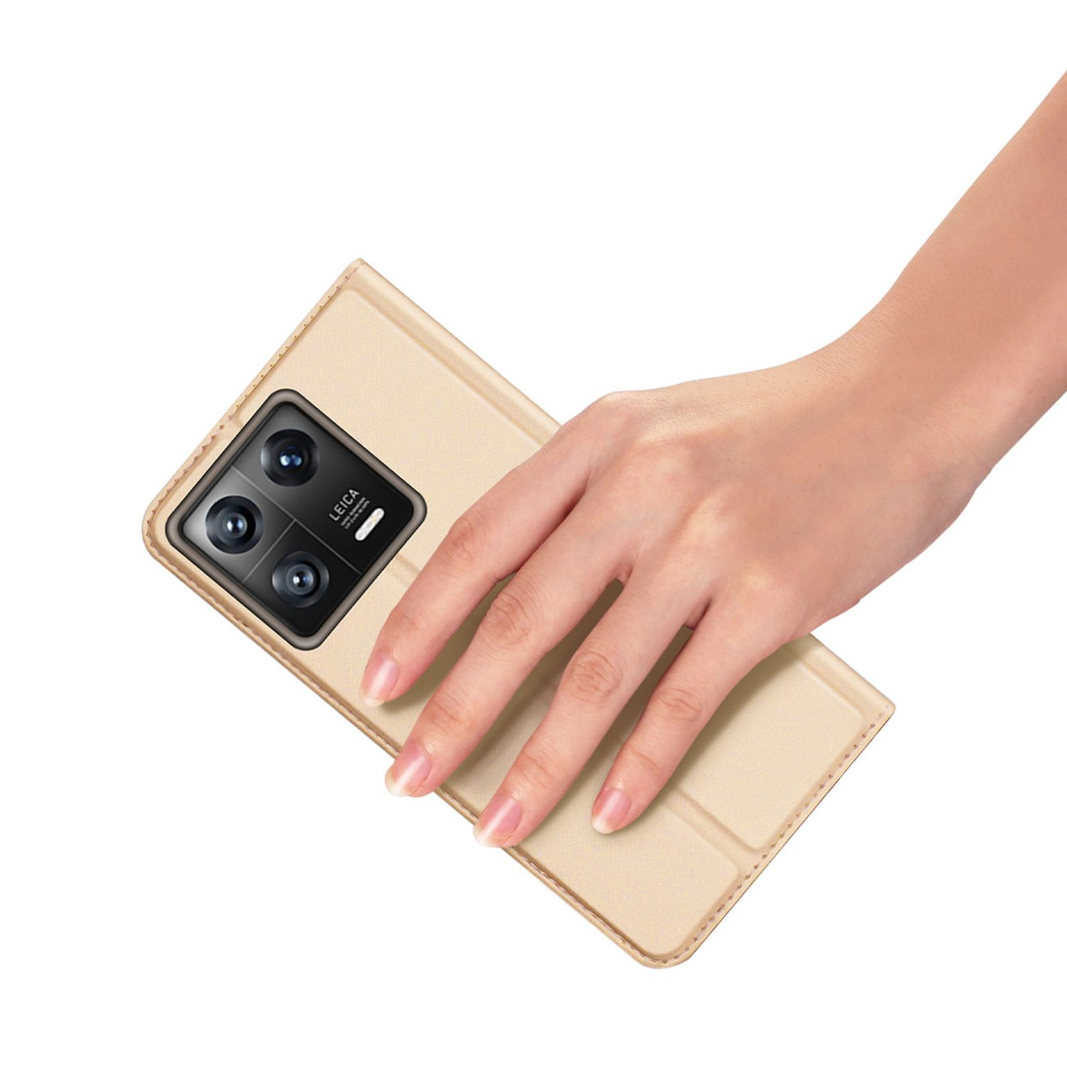 Una mano che tiene una custodia dorata per telefono con un telefono all'interno su sfondo bianco.