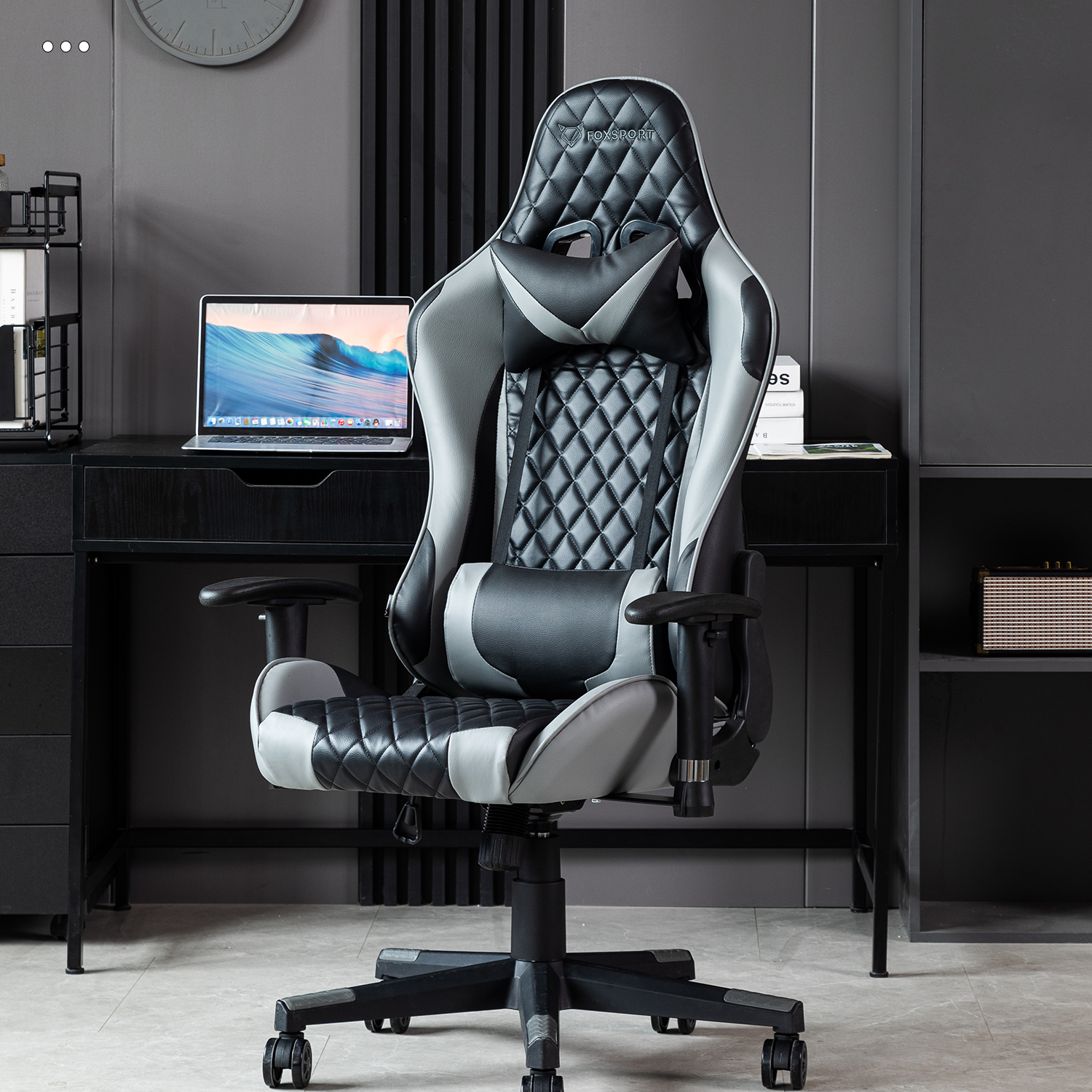 Gaming-Stuhl in Schwarz, Grau und Weiß, mit einem Schreibtisch dahinter.