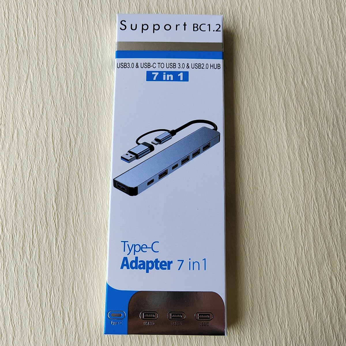 Eine weiß-blaue Box mit einem USB-Hub, der Text '7 in 1' und 'Type-C Adapter'.