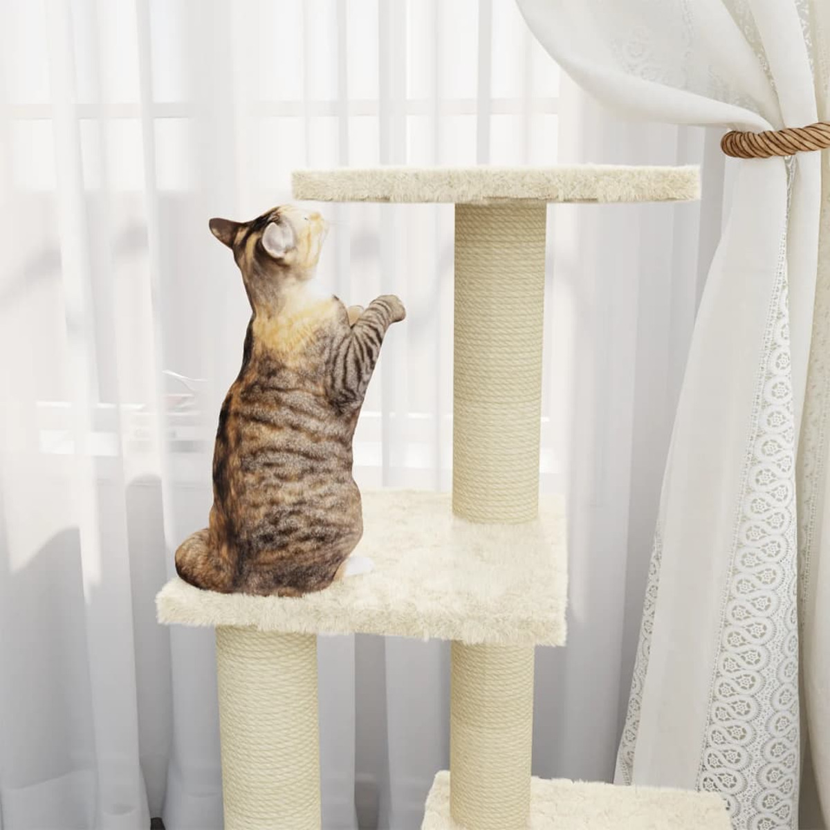 Eine Katze auf einem Katzenbaum, die nach oben schaut. Weiße Vorhänge und Fenster im Hintergrund.