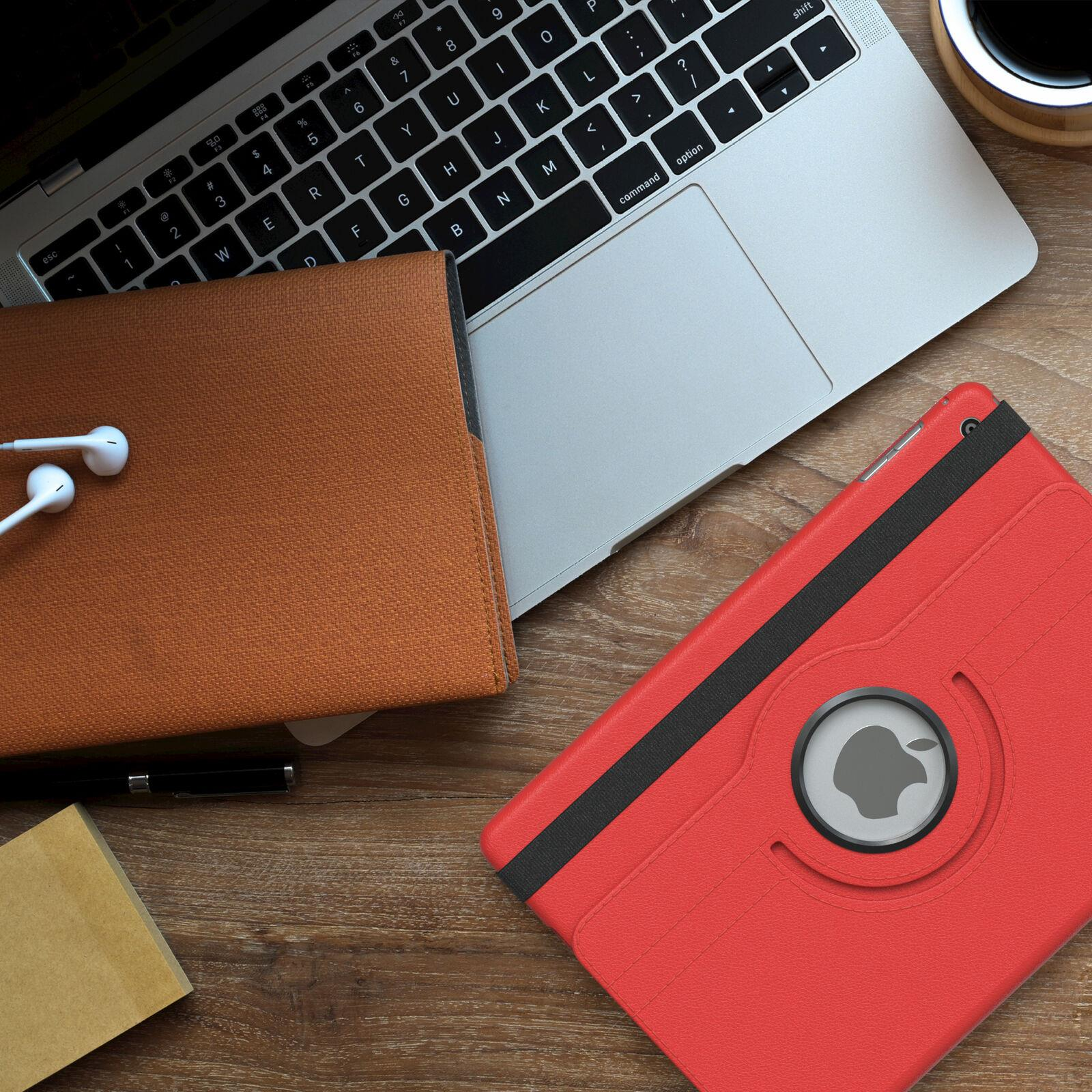 Laptop, rote Tablethülle, braune Hülle und weiße Kopfhörer auf einem Holztisch.