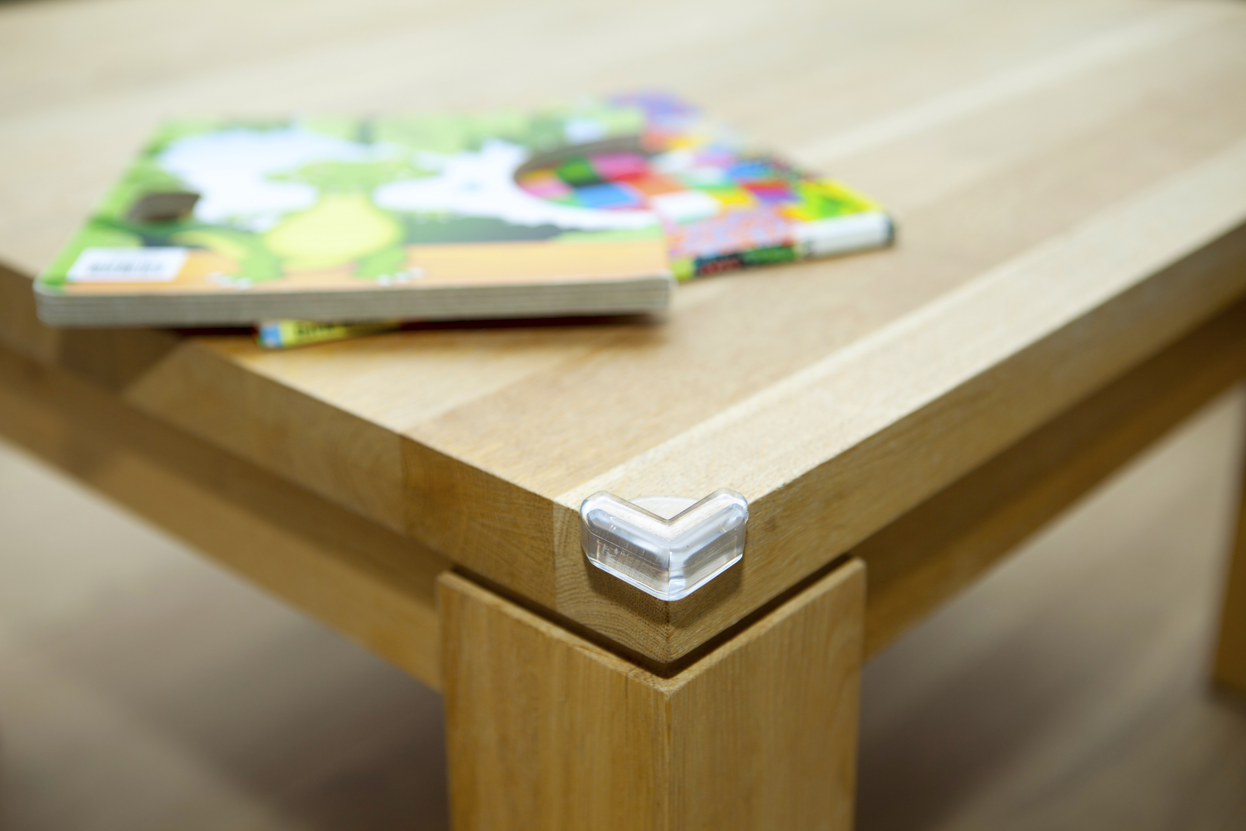 Ecke eines Holztisches mit Buch und Eckenschutz.
