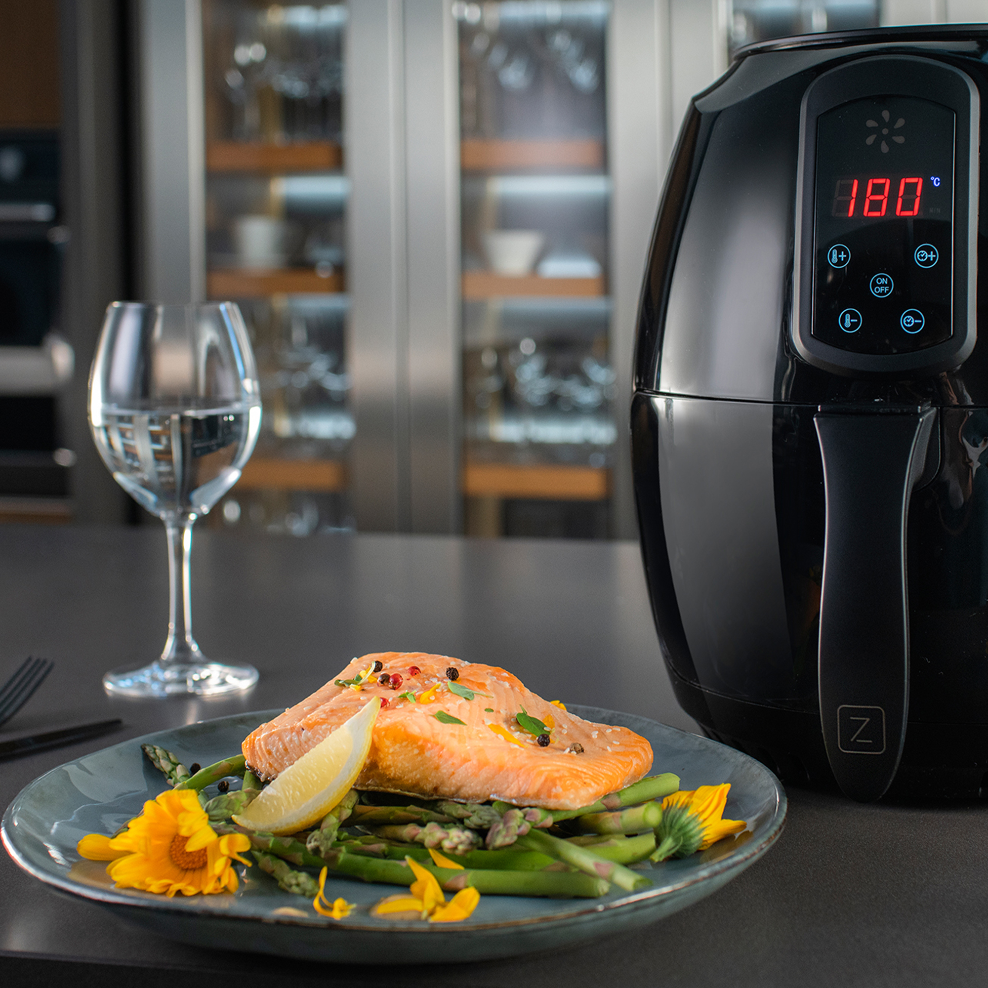 Czarna frytkownica beztłuszczowa z cyfrowym wyświetlaczem pokazującym 180 stopni. Jedzenie na talerzu.