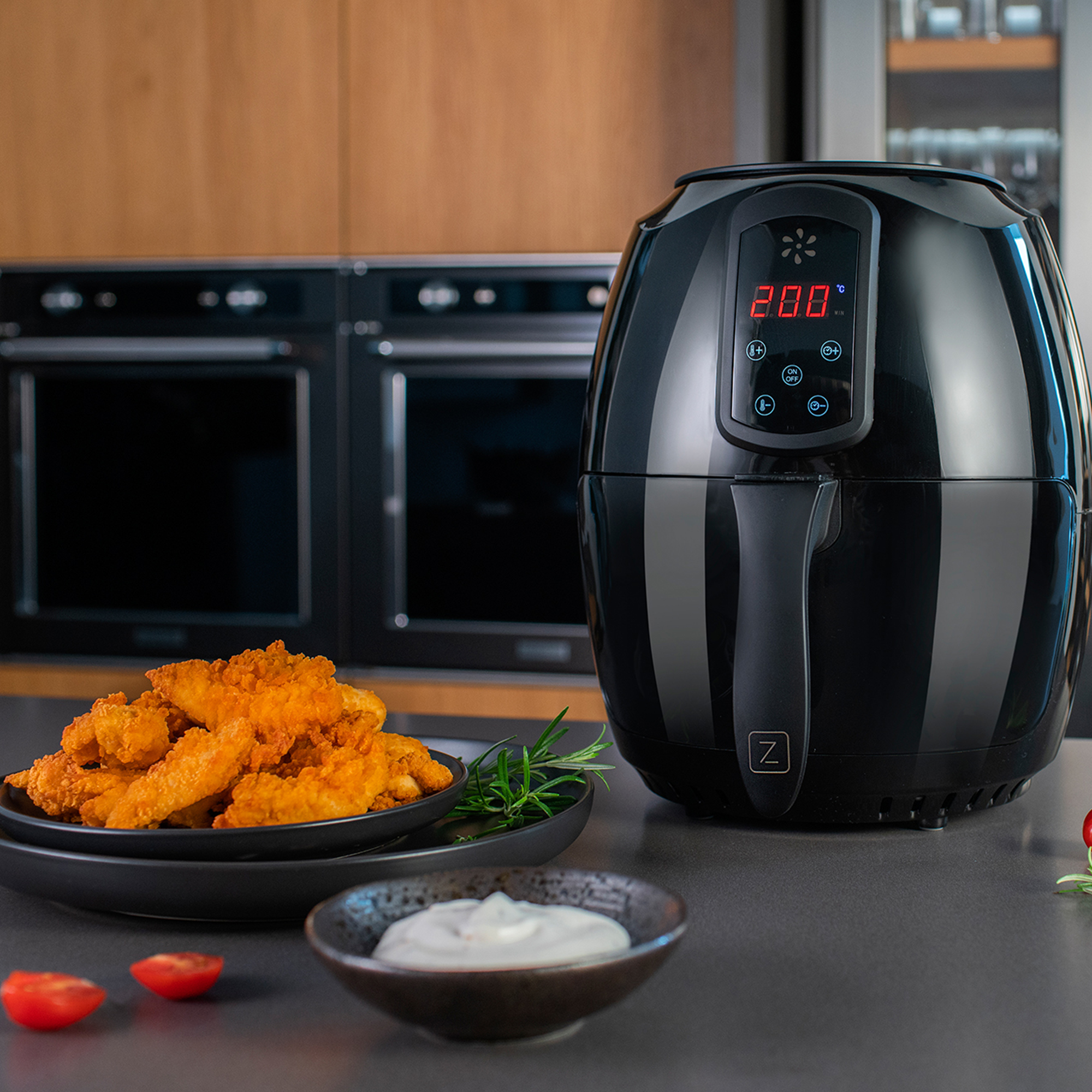 Czarna frytownica powietrzna z kawałkami kurczaka i sosem do maczania.