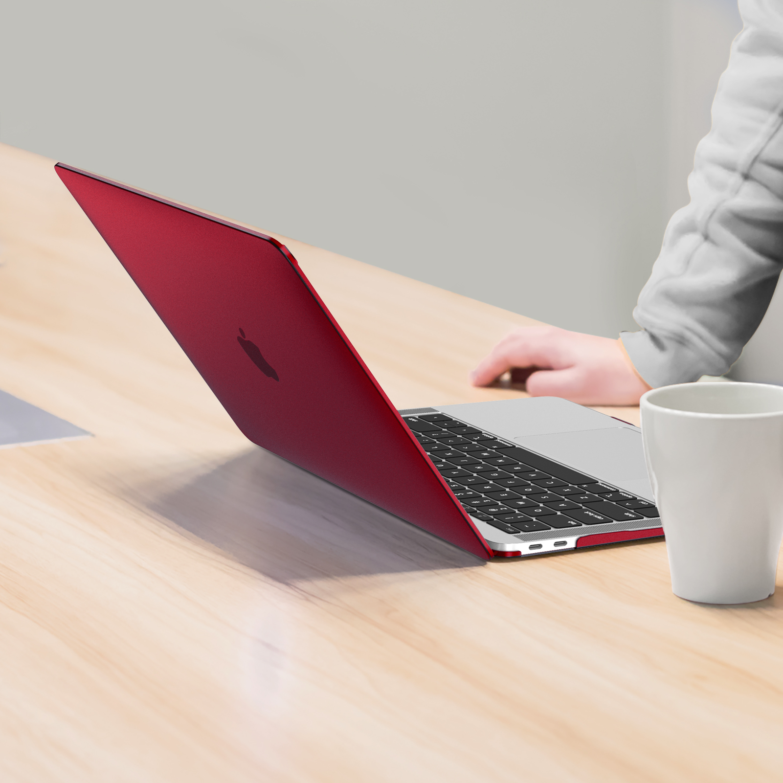 Roter Laptop auf einem Holztisch mit weißem Becher.