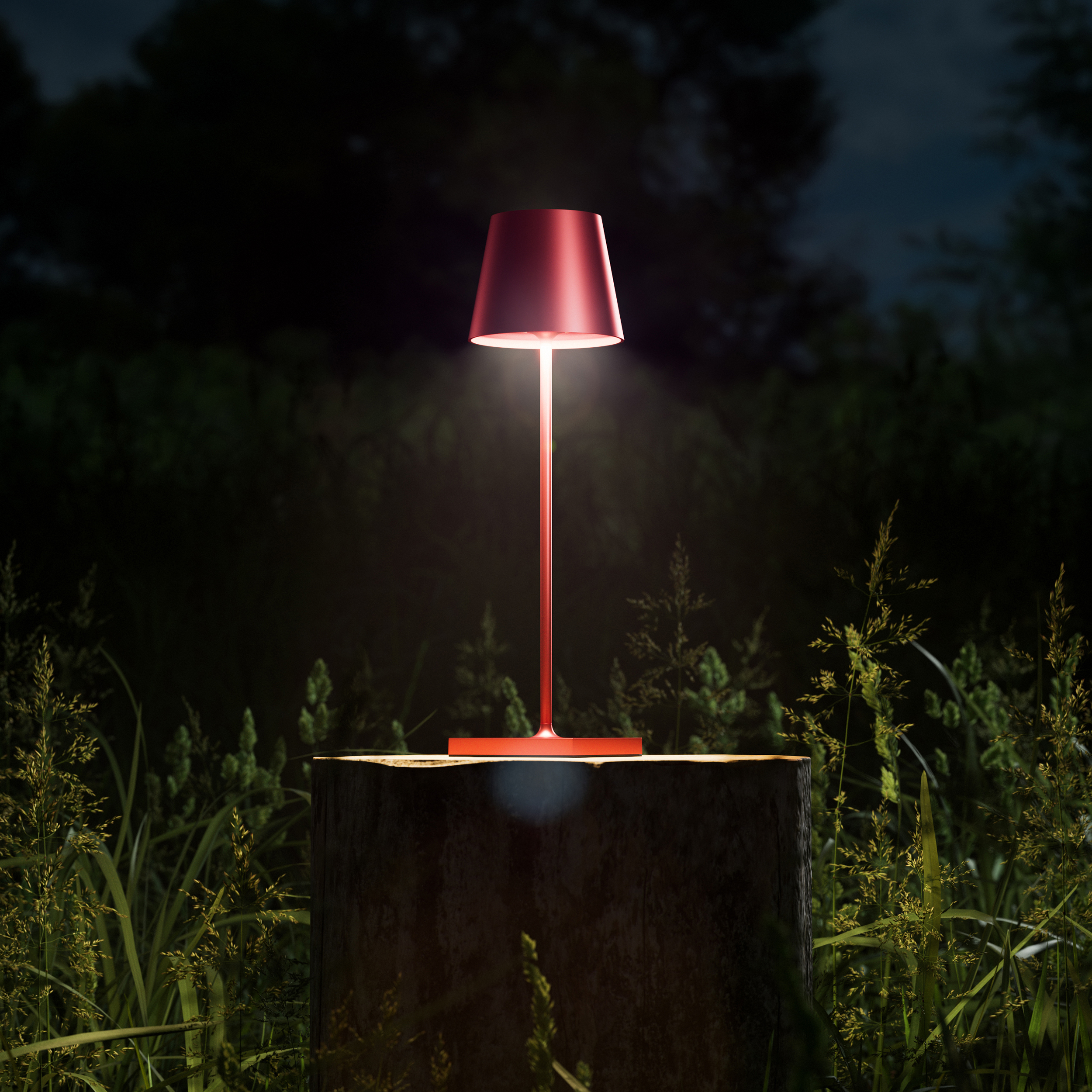 Rote Tischlampe auf einem Baumstumpf, in einem grünen, grasbewachsenen Bereich bei Nacht.