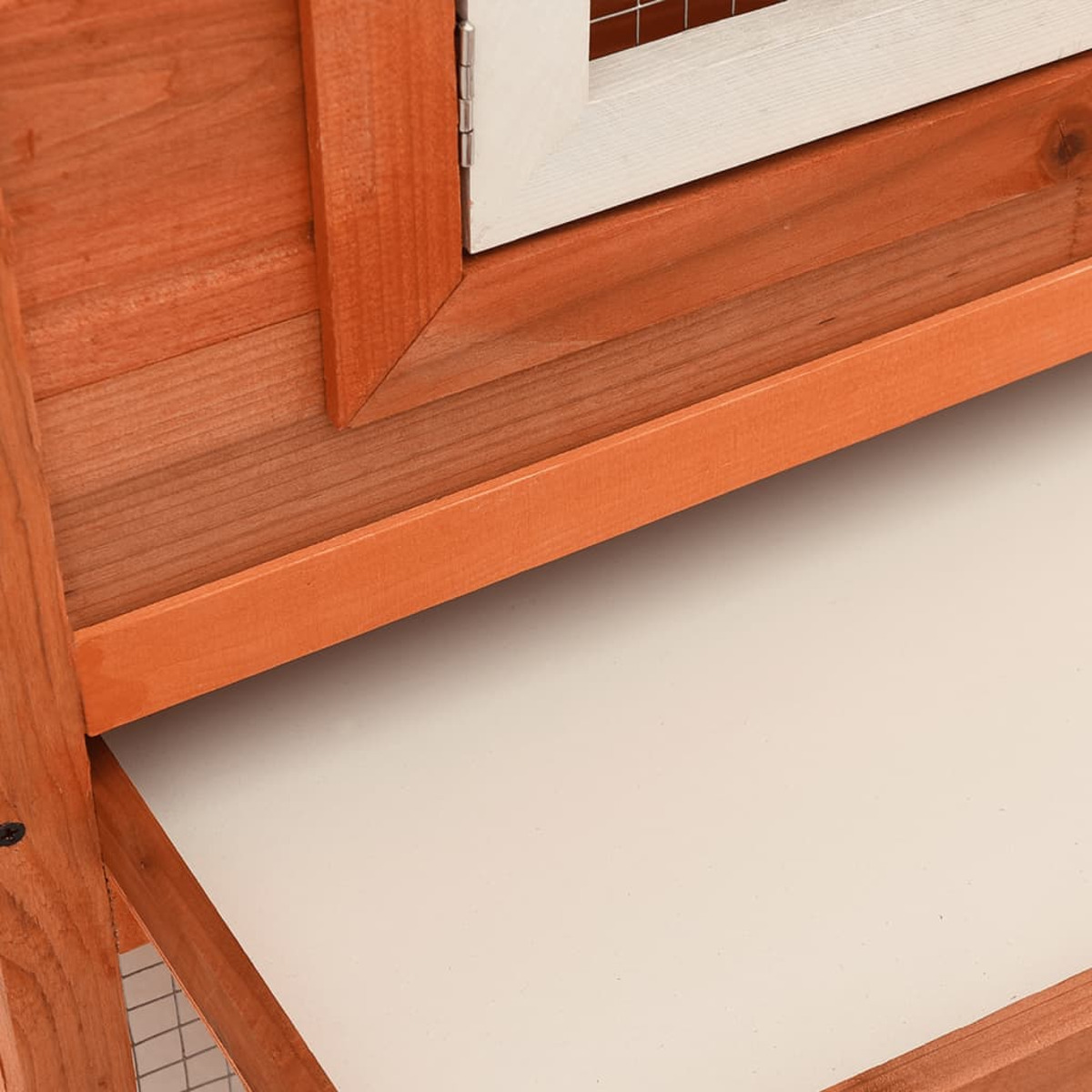 Hühnerstall aus Holz mit weißer Schublade und einem Teil der Tür sichtbar.