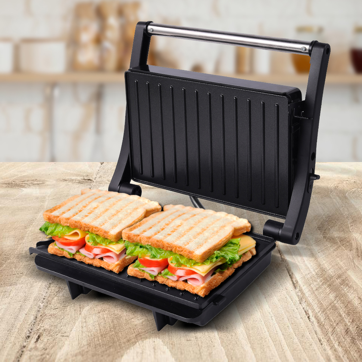 Prensa panini negra abierta con dos sándwiches con queso, jamón, tomate y lechuga.