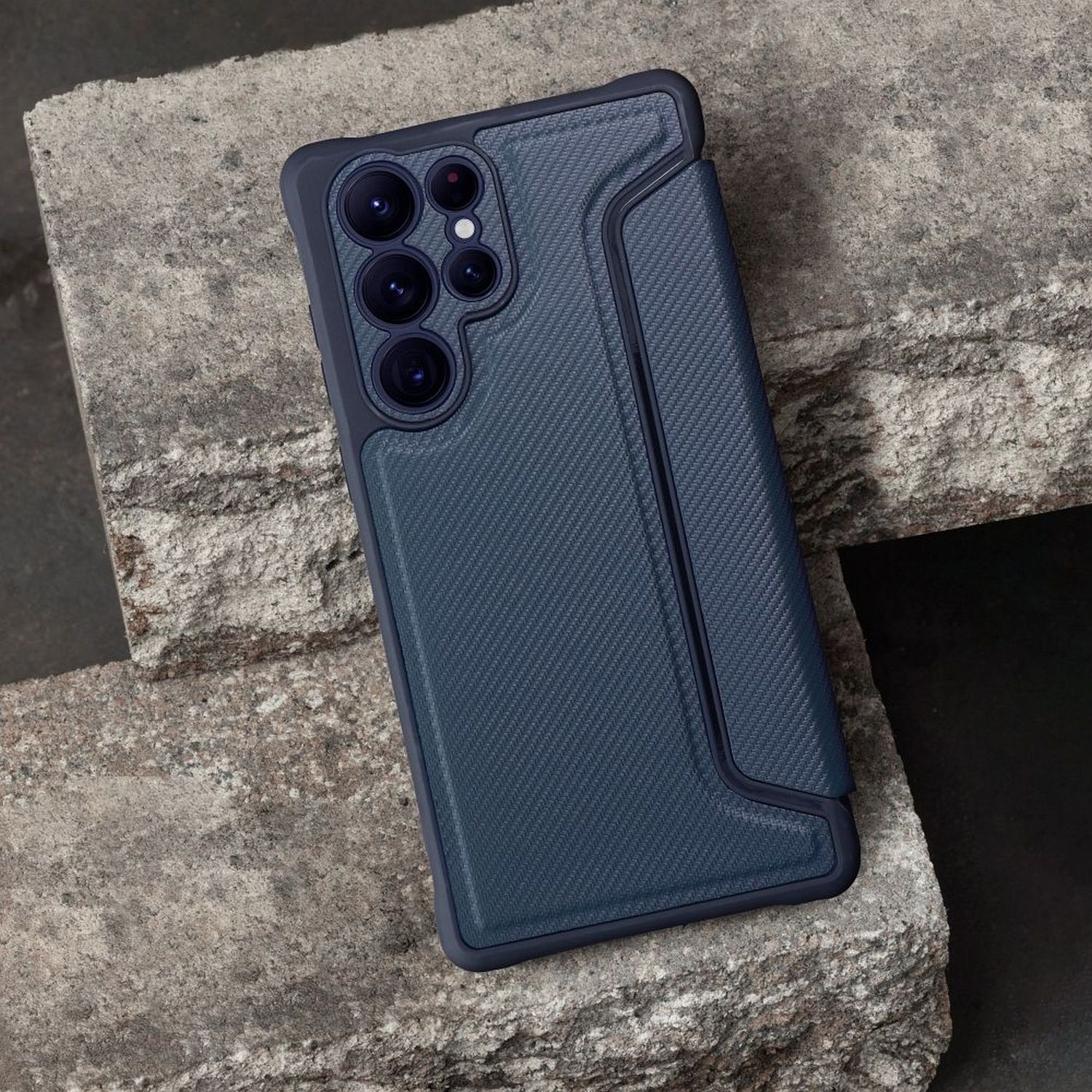 Dunkelblaue Handyhülle auf rauer Steinoberfläche. Mit strukturiertem Design und Kameraaussparungen.