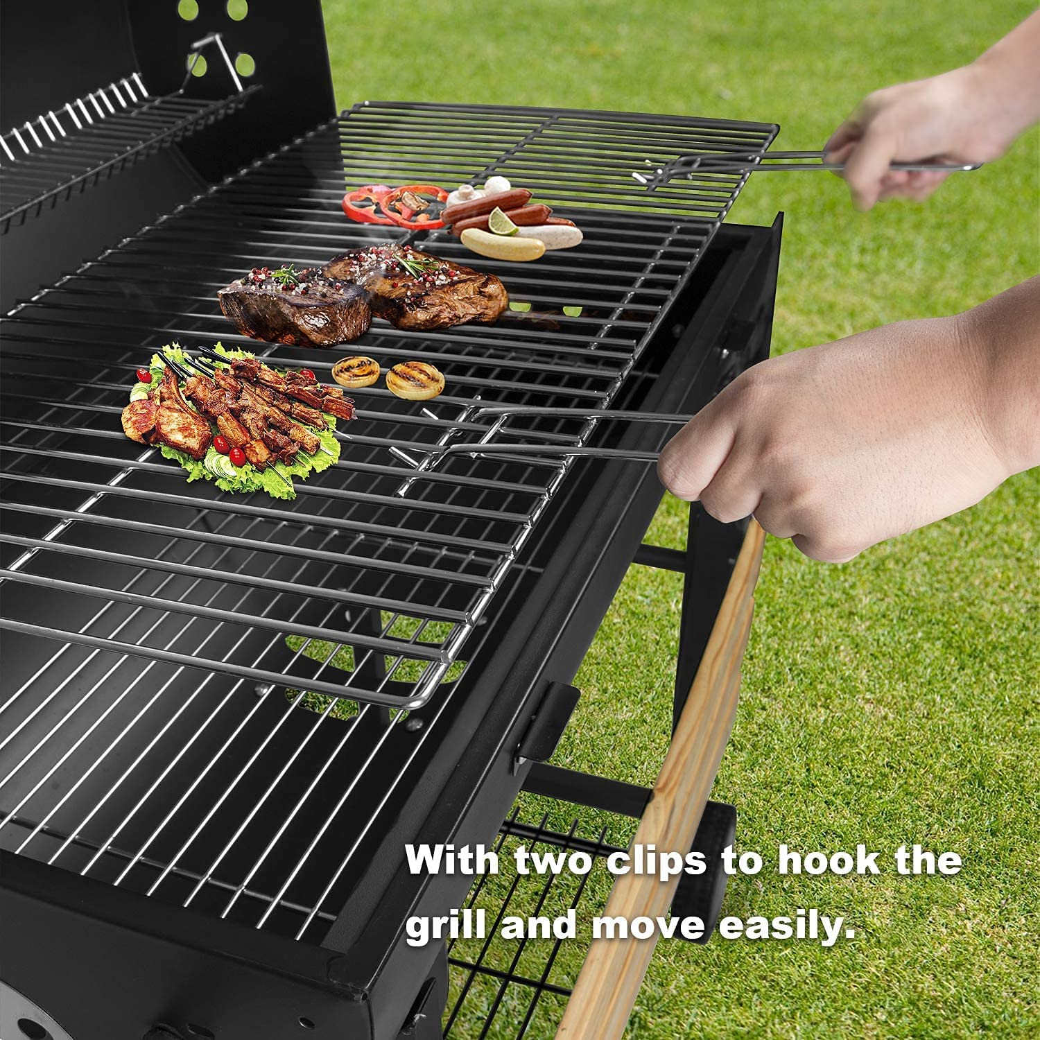 Grill mit Essen, darunter Steaks, Würstchen und Gemüse, auf einer Wiese.