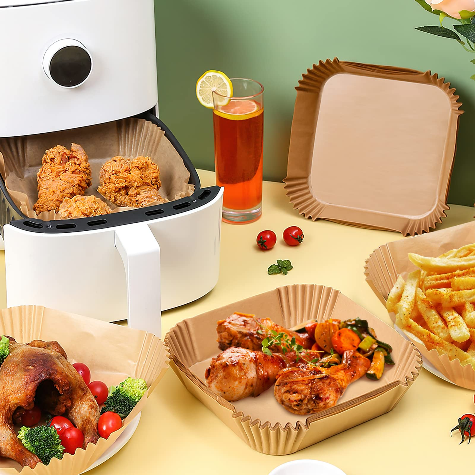Airfryer met gebraden kip, diverse gerechten in papieren bakjes en een glas drank.
