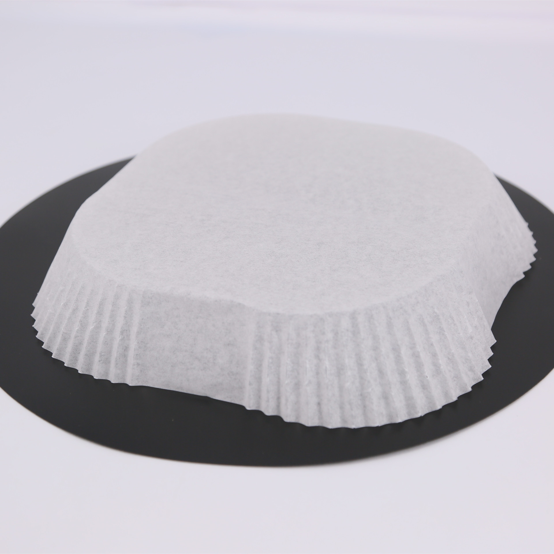 Weißes Papier-Backpapier auf schwarzer Oberfläche. Die Form ist rund.