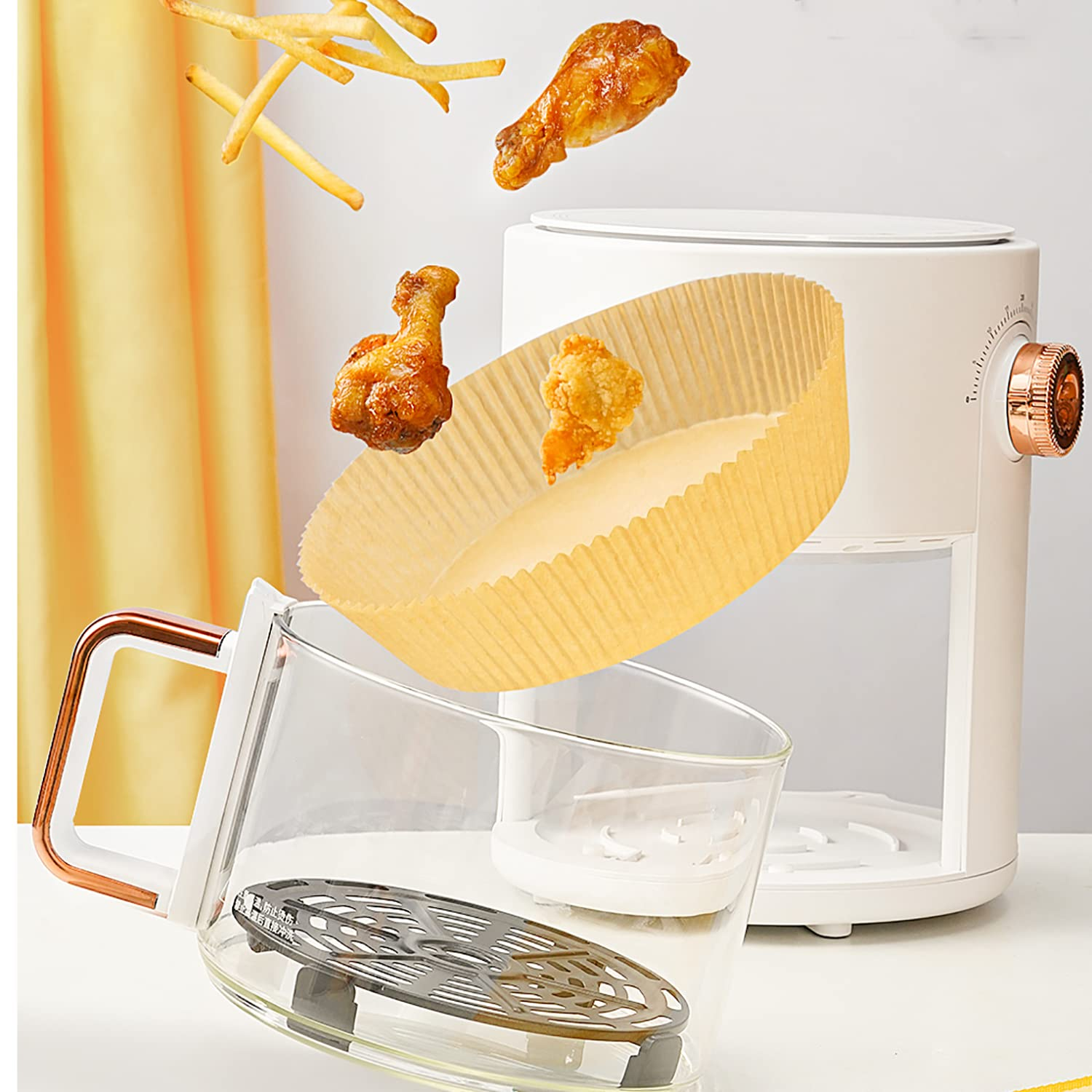 Eine Heißluftfritteuse mit frittierten Speisen. Hühnchen und Pommes fliegen in einen Glasbehälter.