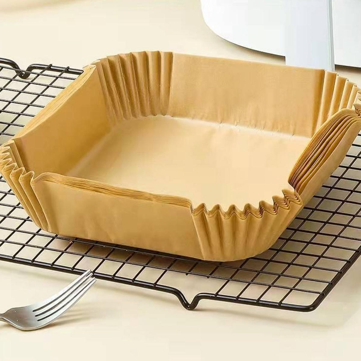 Stos brązowych papierowych foremek do pieczenia na drucianym ruszcie, z widelcem.