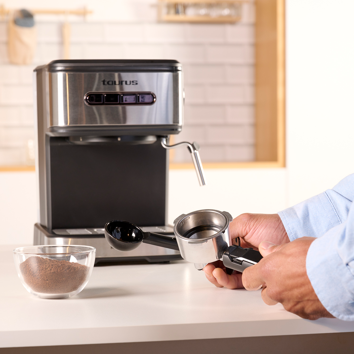 Osoba przygotowuje kawę za pomocą ekspresu do kawy Taurus i akcesoriów na białym stole.