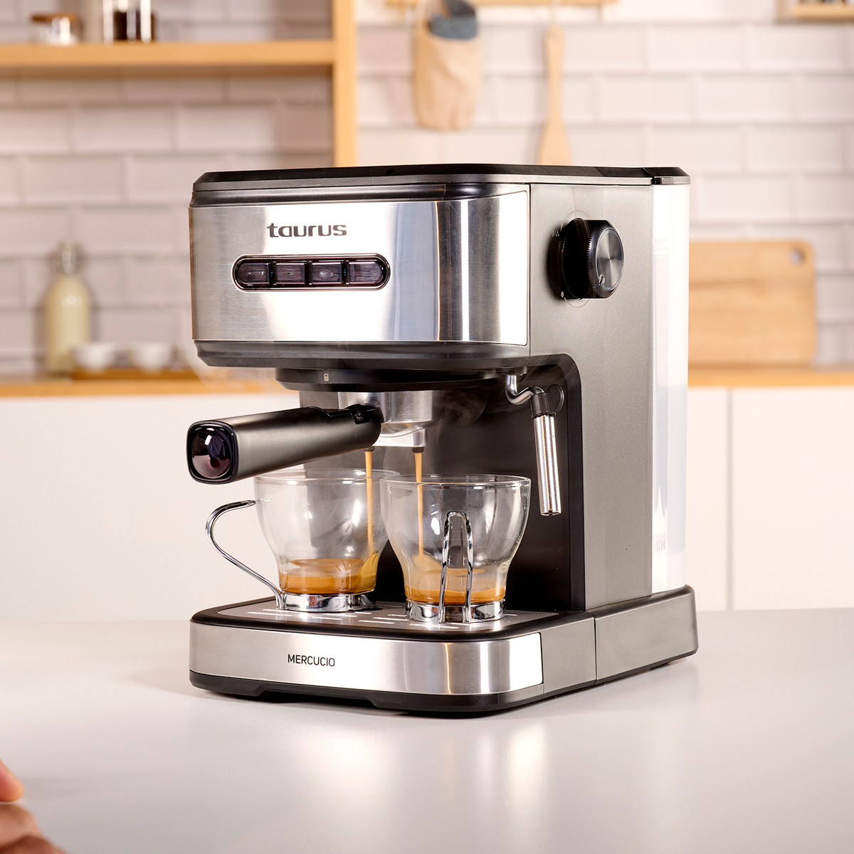 Ekspres do kawy Taurus parzący kawę do dwóch przezroczystych szklanek. Maszyna stoi na białej powierzchni.