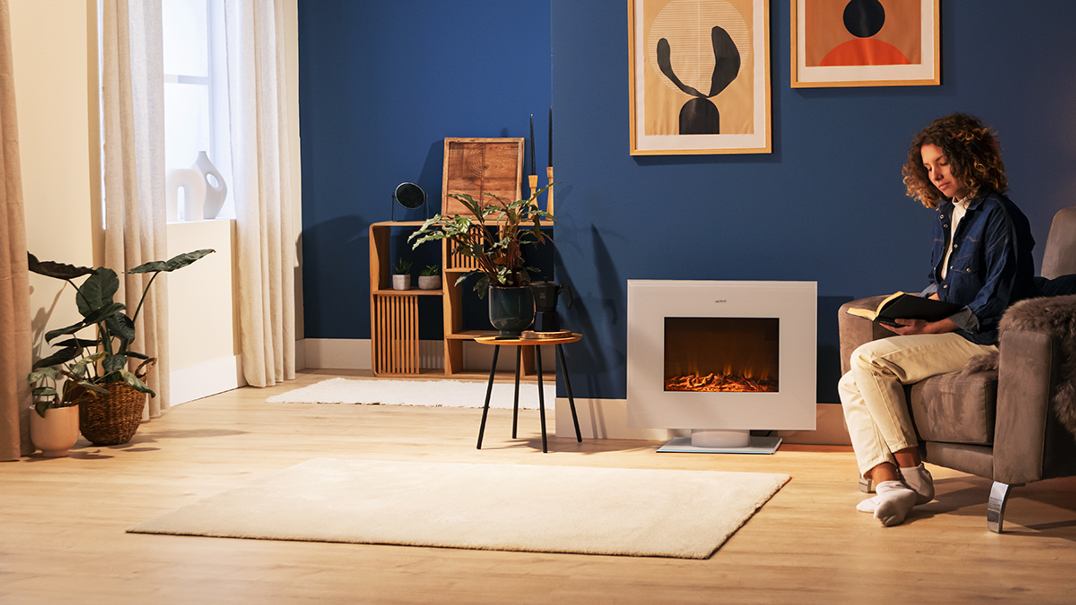 Frau liest am weißen Kamin, blaue Wand, Holzregale mit Pflanzen, Teppich und Fenster.