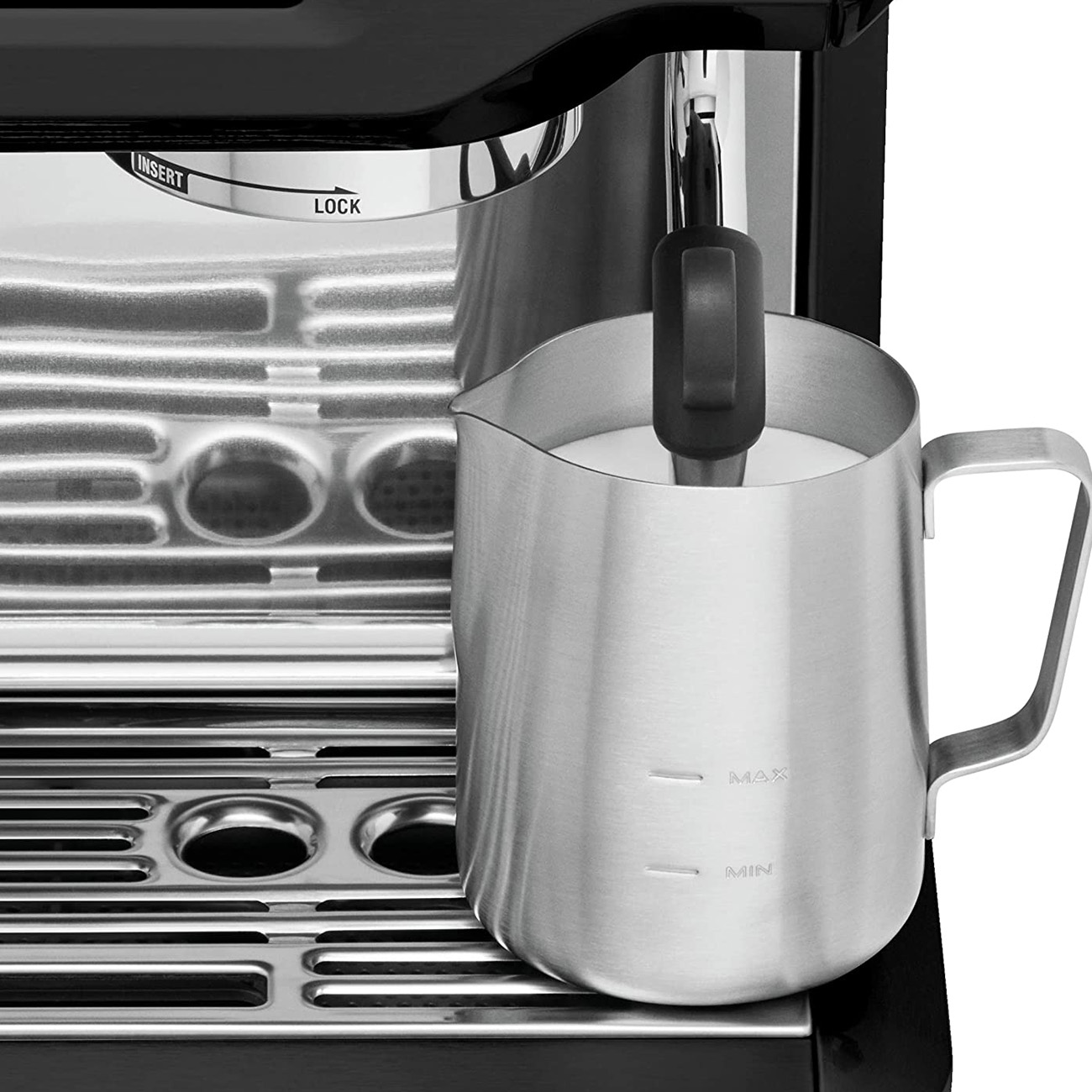 Dzbanek do spieniania mleka ze stali nierdzewnej obok ekspresu do kawy.