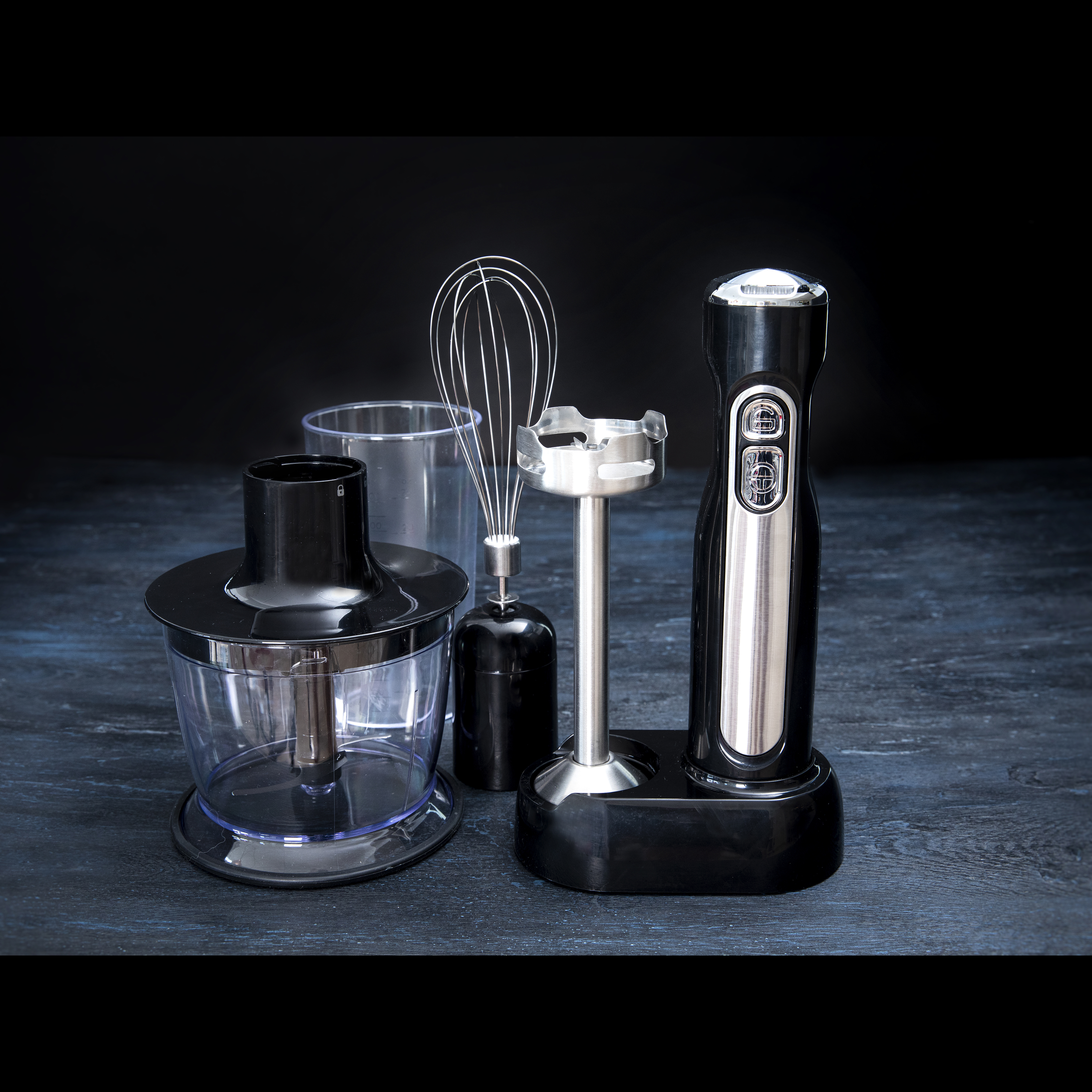 Ein schwarzes Stabmixer-Set mit mehreren Aufsätzen, darunter ein Schneebesen, ein Zerkleinerer und ein Mixstab.