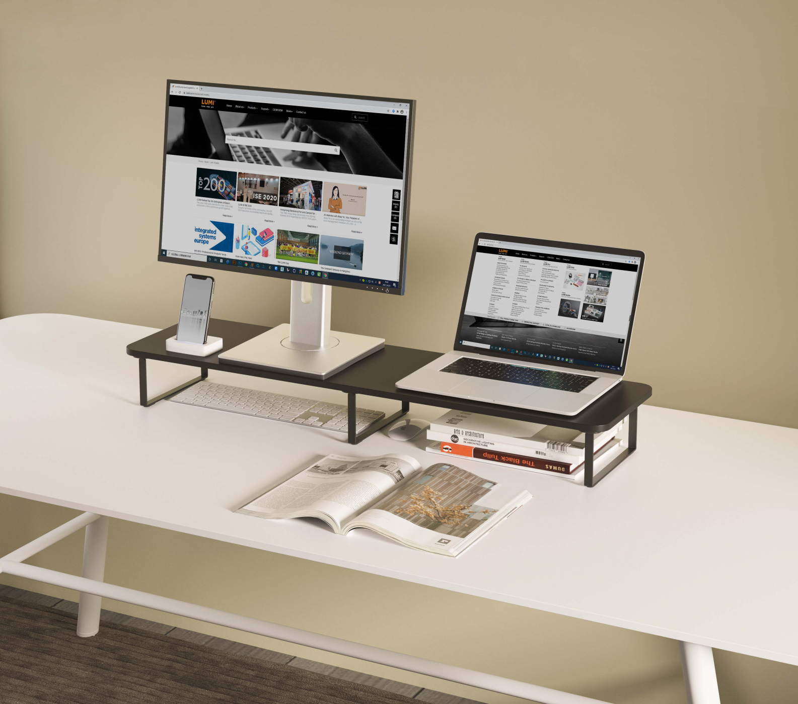 Schreibtisch-Setup mit Monitor, Laptop, Telefon, Tastatur, Büchern und Zeitschrift. Neutraler Hintergrund.
