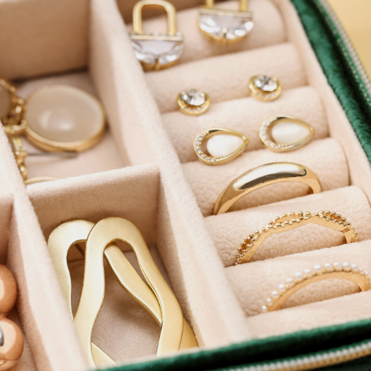 Geöffnete Schmuckschatulle, gefüllt mit goldenen Ohrringen, Ringen und einer Halskette.