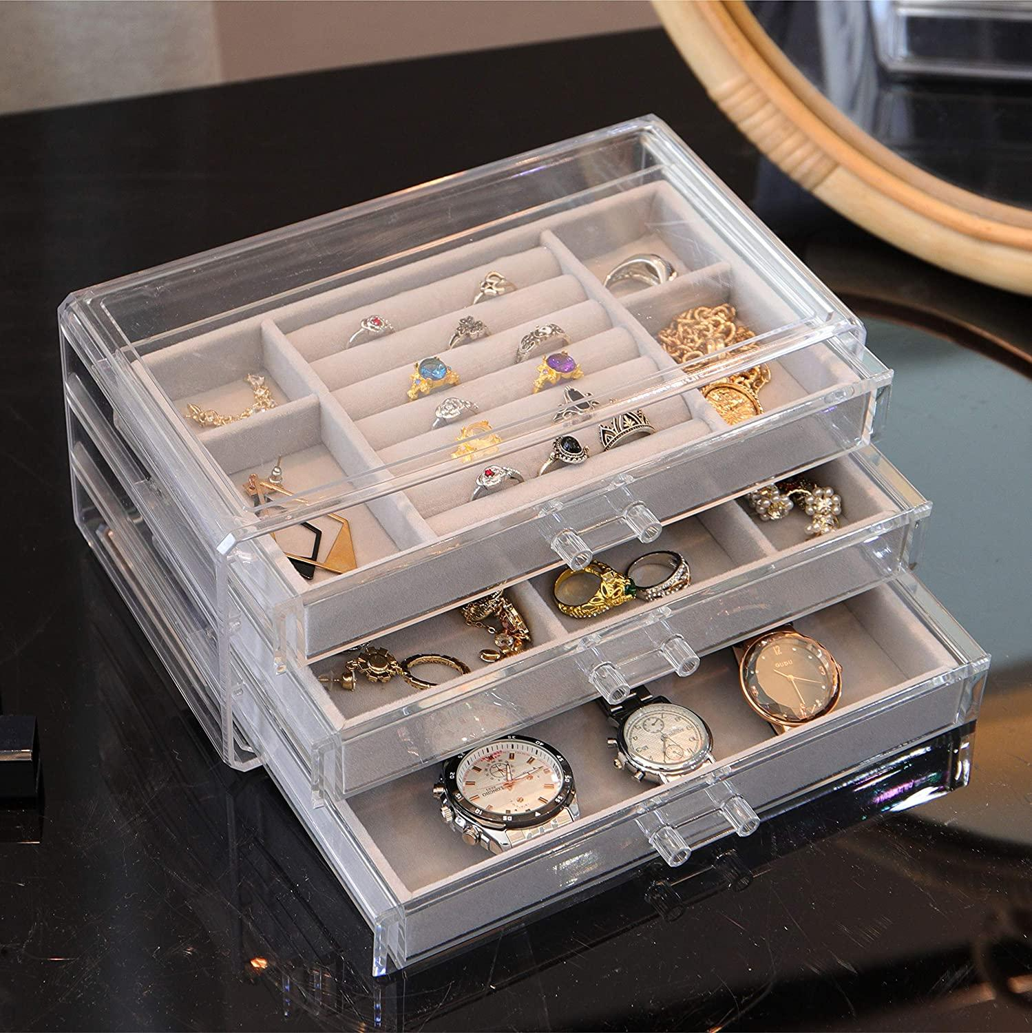 Schmuck-Organizer mit zwei Schubladen, gefüllt mit Ringen, Halsketten und Uhren, auf dunkler Oberfläche.