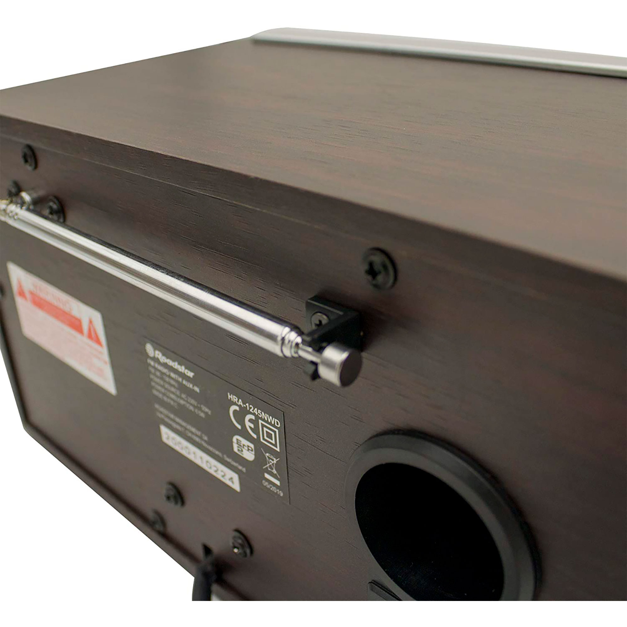 Zbliżenie brązowego radia z anteną. Z tyłu znajdują się etykiety i port głośnikowy.