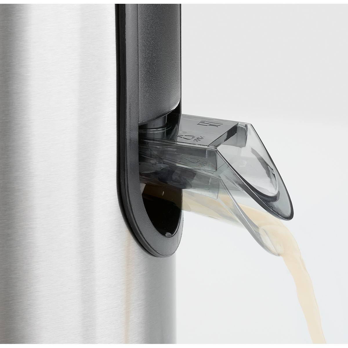 Sok wylewający się ze srebrnej wyciskarki z czarnym detalem. Białe tło.