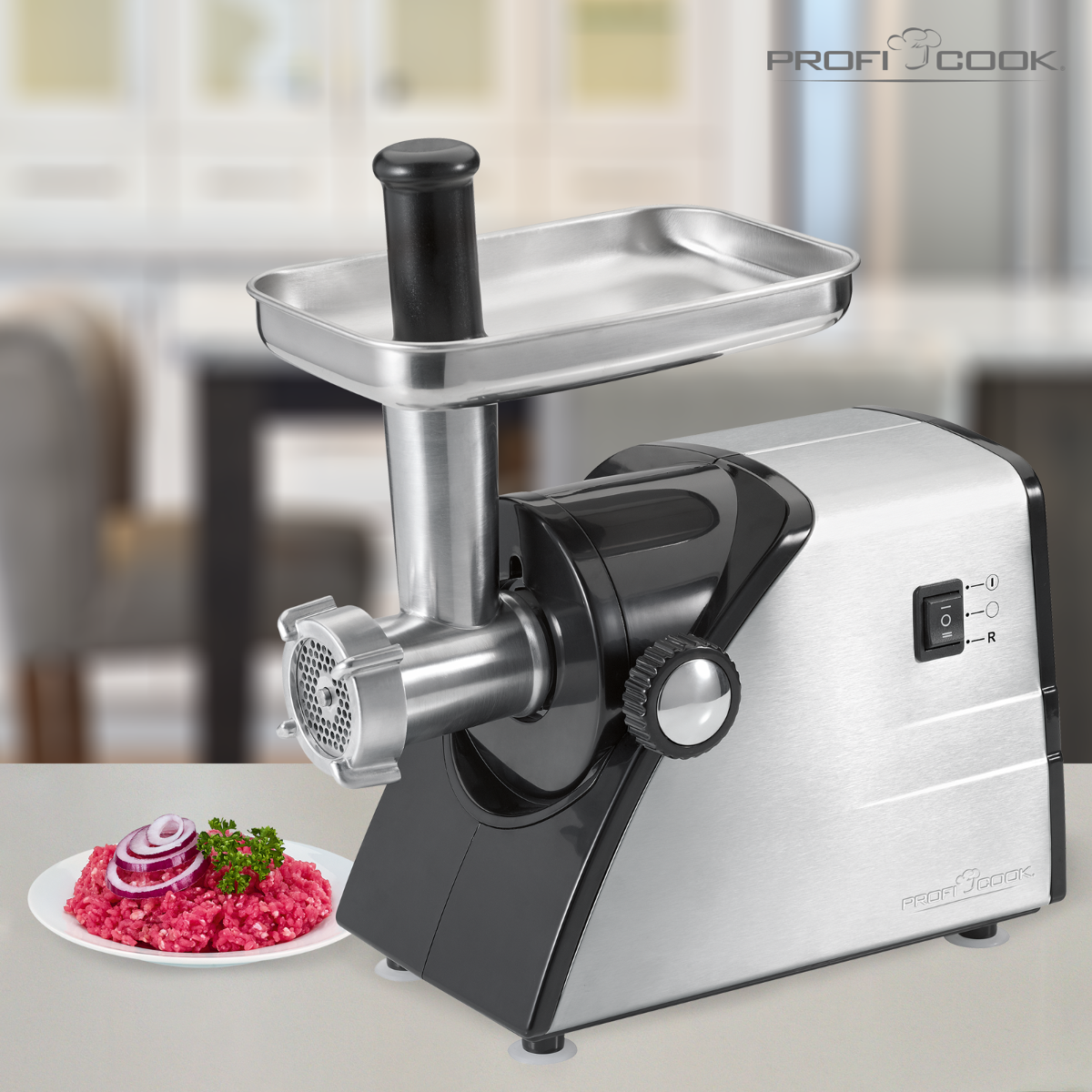 Srebrno-czarna maszynka do mięsa z mięsem na talerzu. Urządzenie kuchenne na białej powierzchni.