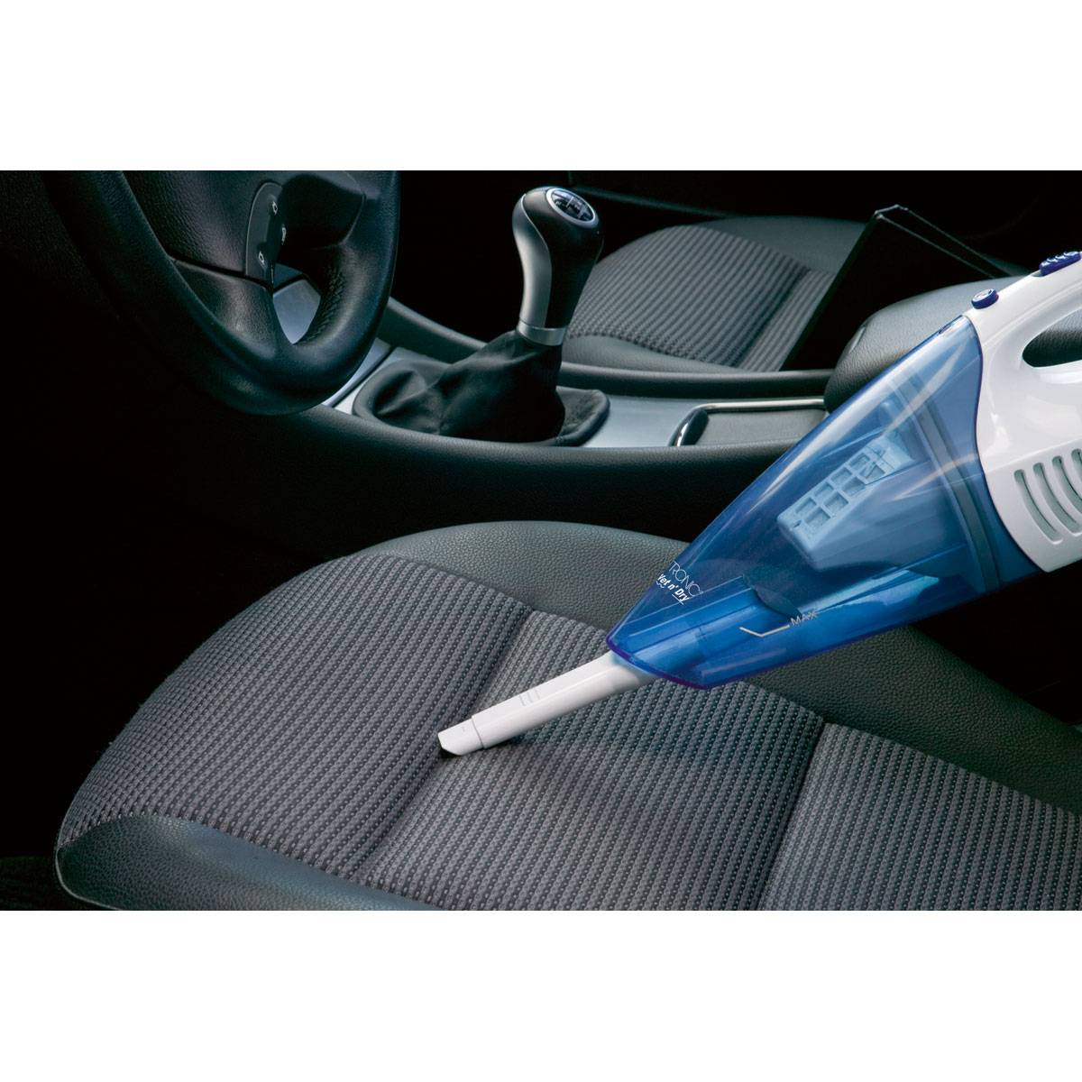 Ręczny odkurzacz odkurza siedzenie w samochodzie, czyszcząc wnętrze niebiesko-białym odkurzaczem.