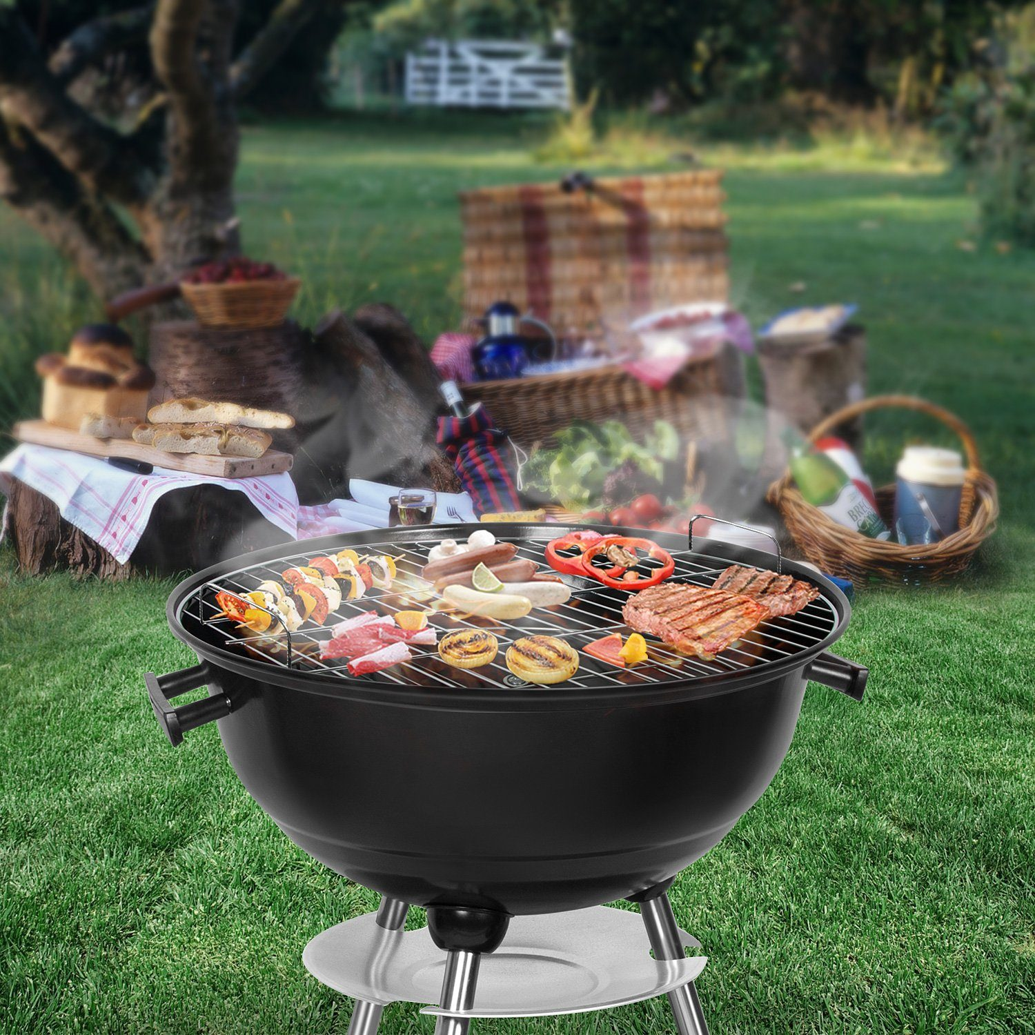 Schwarzer Grill mit Essen, in einem grasbewachsenen Bereich. Auf der Seite gibt es einen Picknickkorb und Essen.