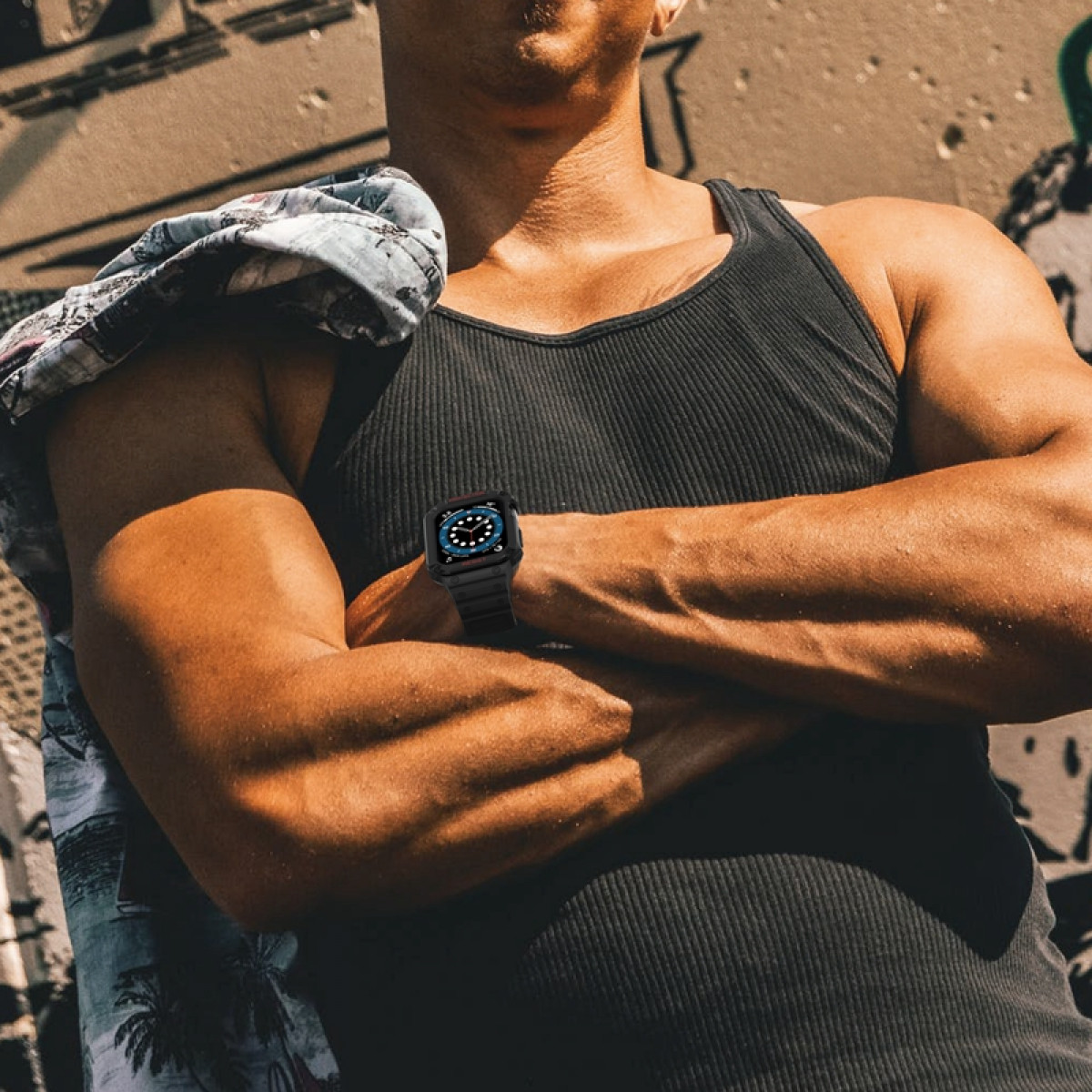 Ein Mann mit verschränkten Armen, der eine Apple Watch trägt, Graffiti-Wand im Hintergrund.
