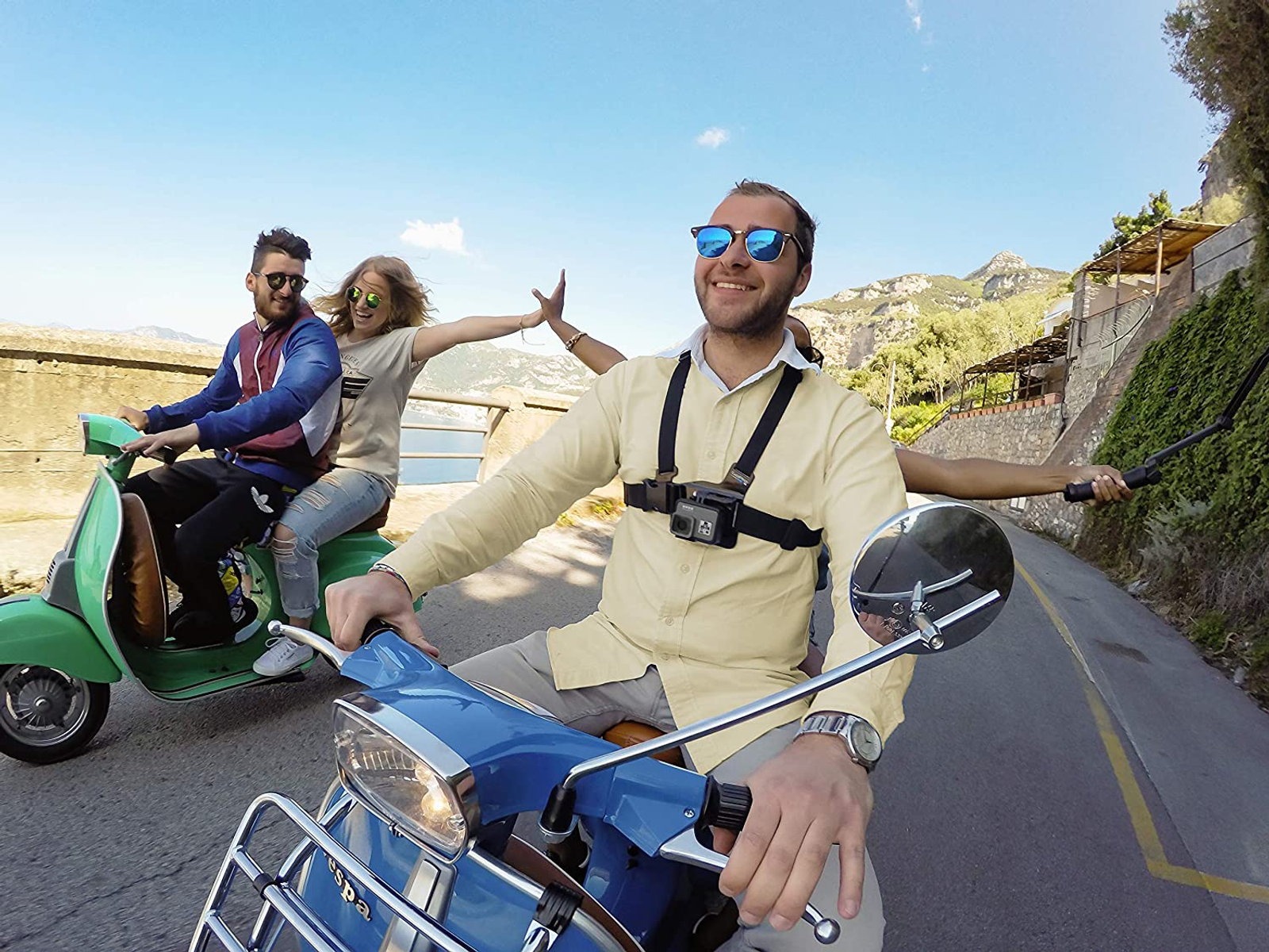 Trzy osoby na skuterach, jedna z przodu w okularach przeciwsłonecznych, dwie z tyłu.