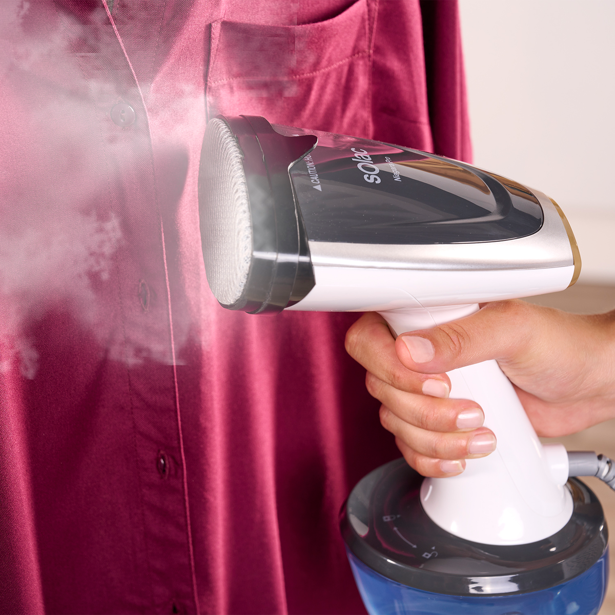 Eine Person, die ein rotes Hemd mit einem Handdampfer bedampft.