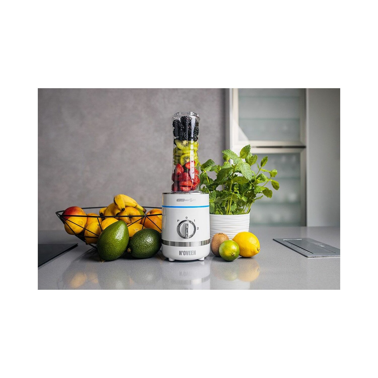 Blender z owocami w środku. Banany, awokado, kiwi, cytryny i miska z owocami.