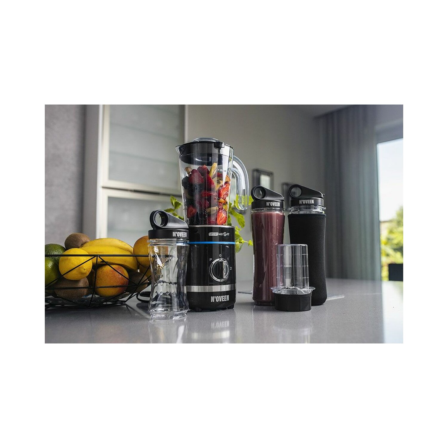 Blender z czarną podstawą i szklanym słoikiem, z owocami i innymi akcesoriami.