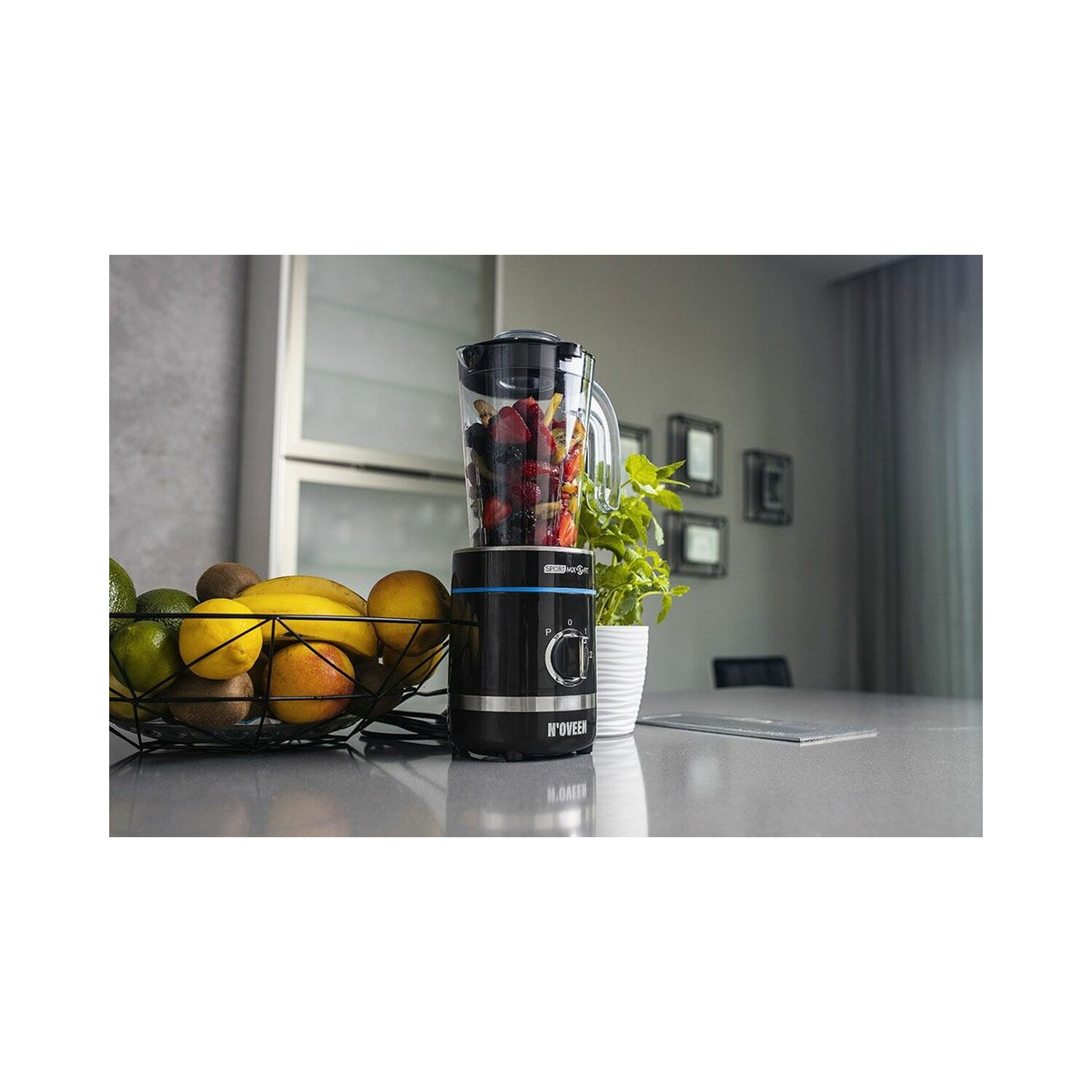 Czarny blender z owocami i warzywami obok miski z owocami.