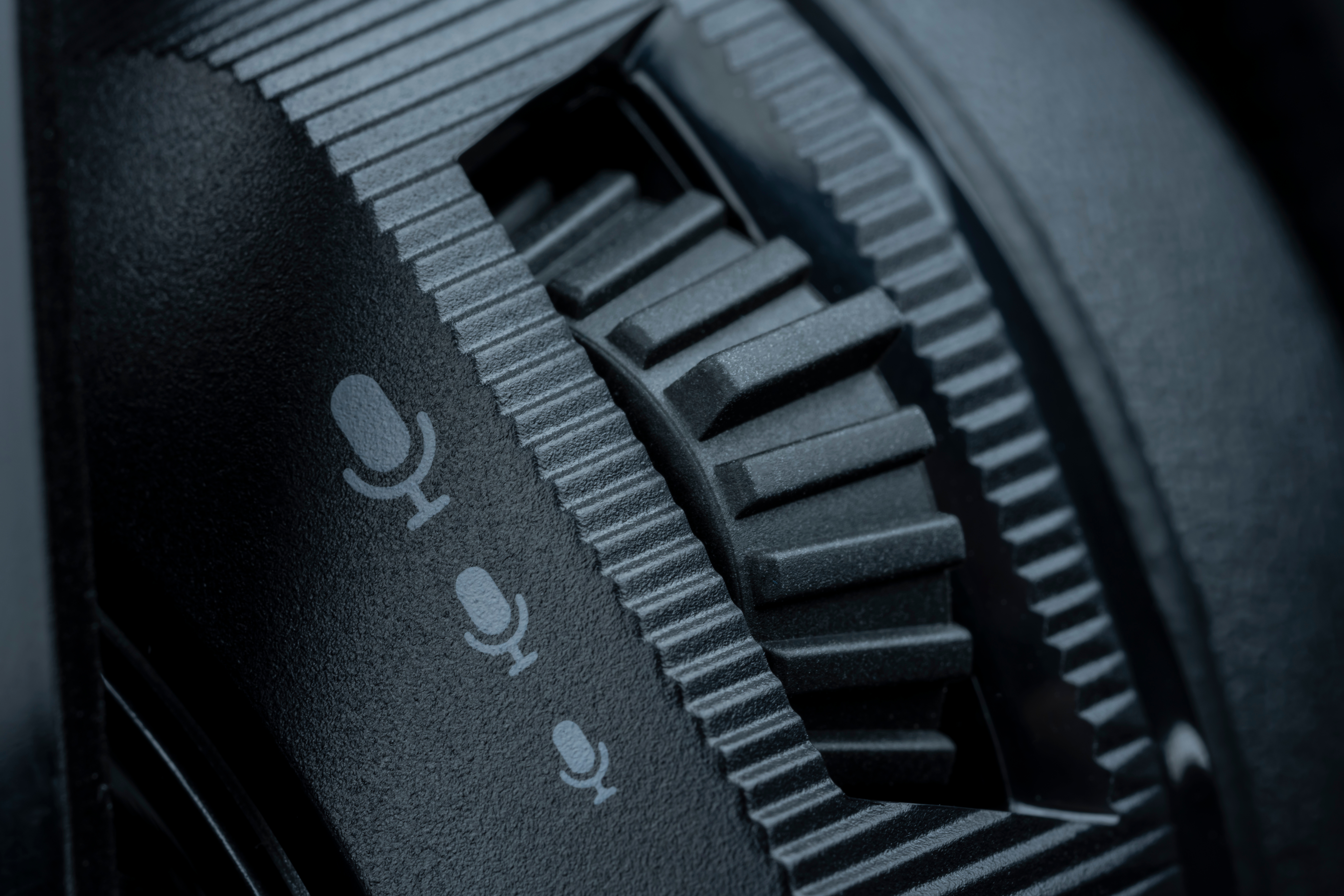 Zbliżenie czarnego pokrętła głośności mikrofonu z ikonami mikrofonu.