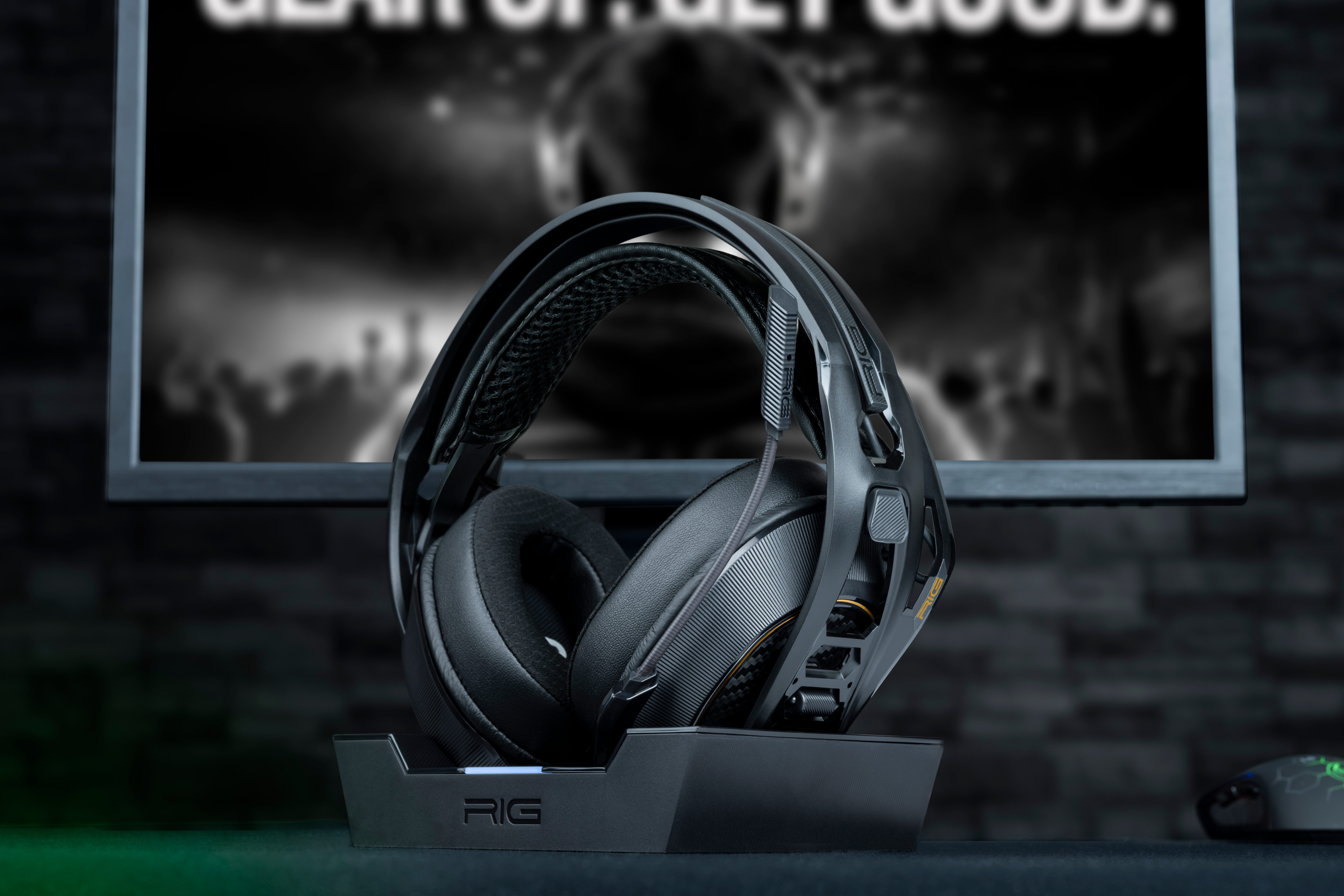 Ein schwarzes Headset auf einem Ständer vor einem Monitor.